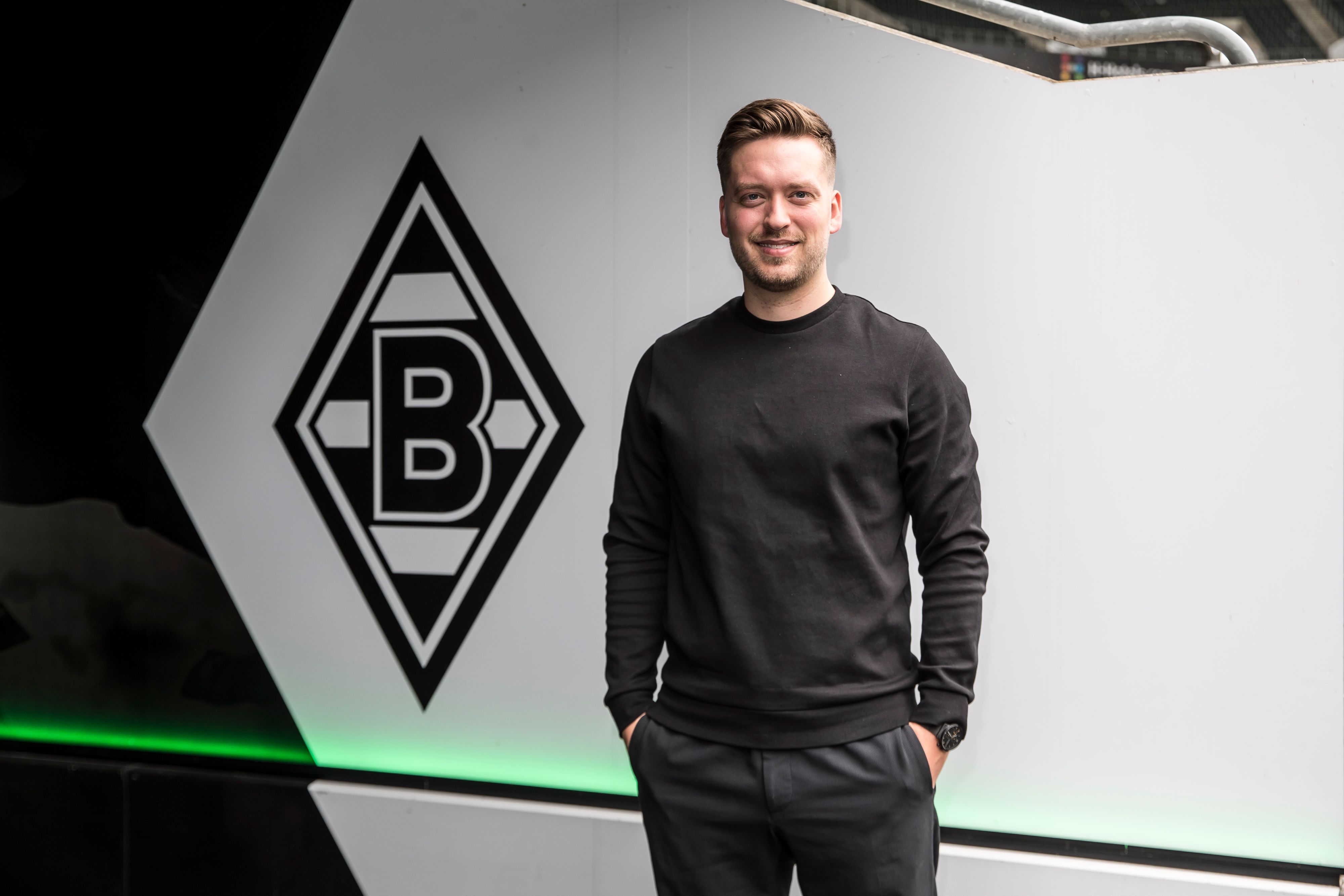 Jonas Spengler, Trainer des Frauen-Teams von Borussia Mönchengladbach. Er steht vor ener Borussia-Raute.