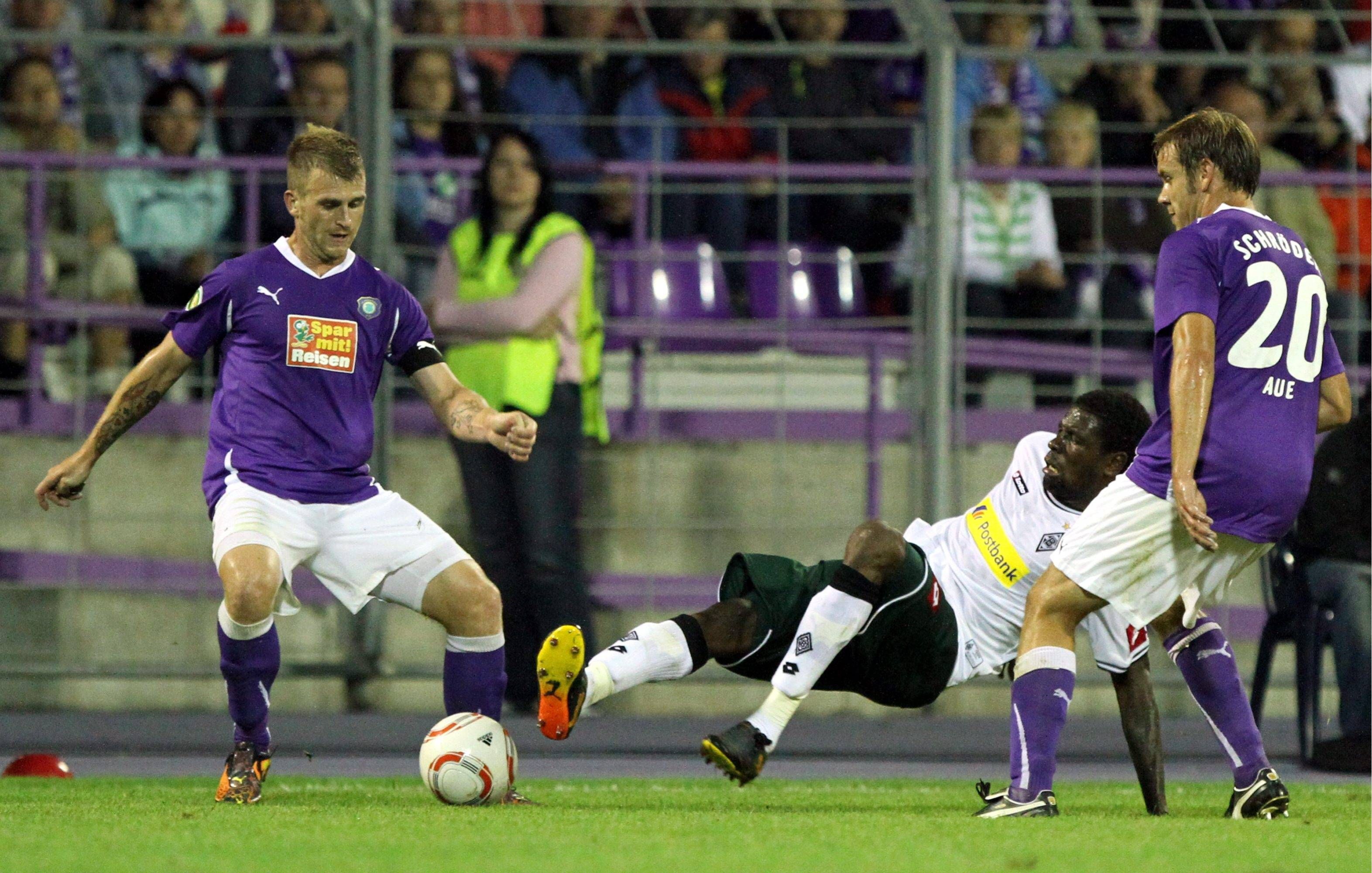 René Klingbeil (l.) und Mo Idrissou (M.) kämpfen im Spiel von Erzgebirge Aue gegen Borussia Mönchengladbach am 14. August 2010 um den Ball.