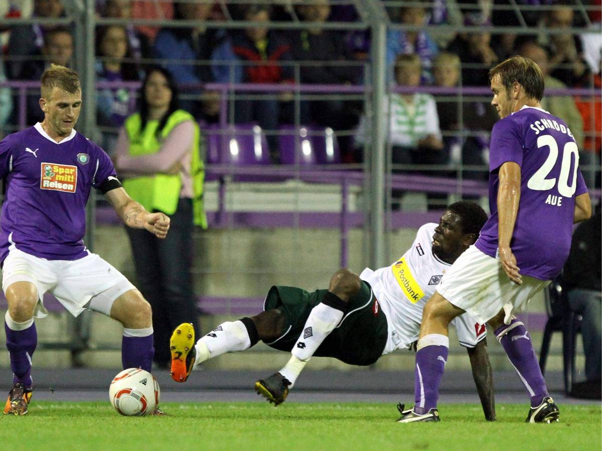 René Klingbeil (l.) und Mo Idrissou (M.) kämpfen im Spiel von Erzgebirge Aue gegen Borussia Mönchengladbach am 14. August 2010 um den Ball.