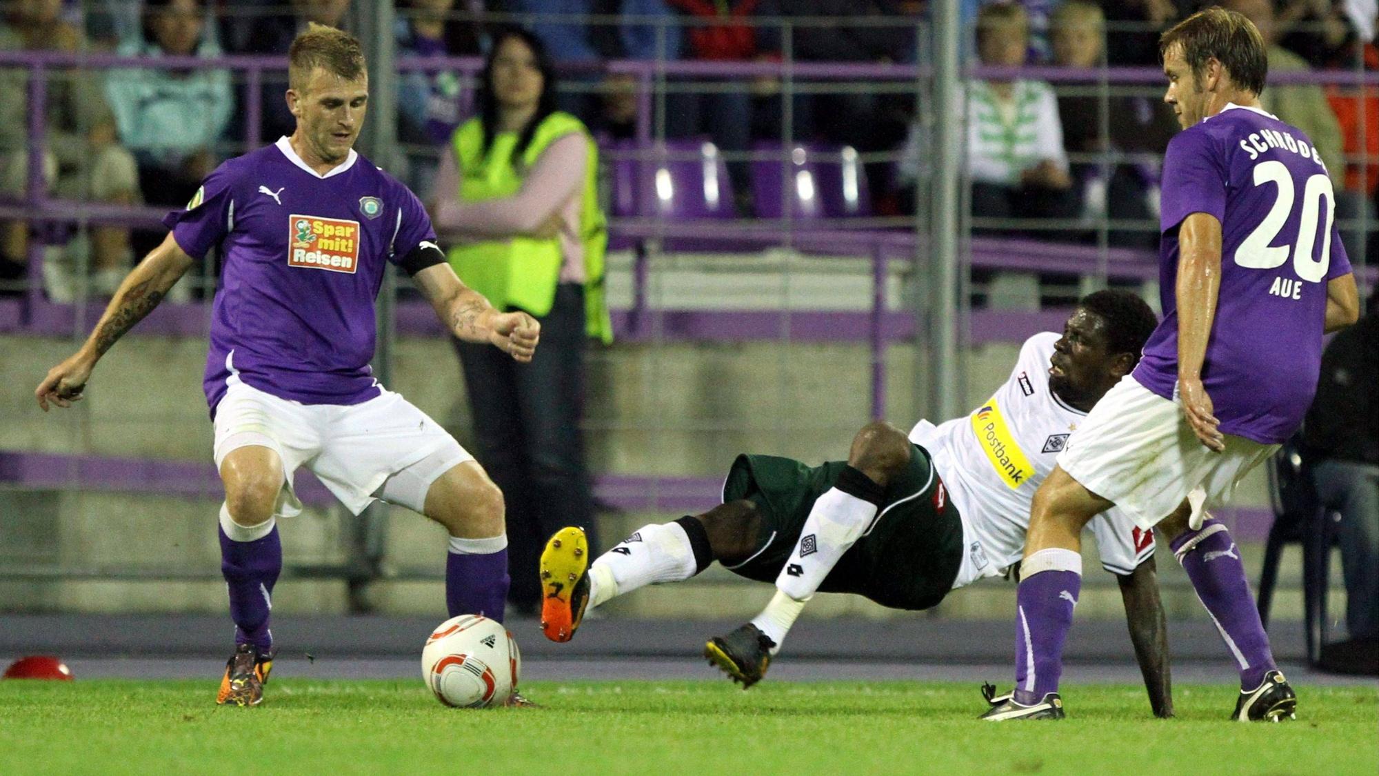 René Klingbeil (l.) und Mo Idrissou (M.) kämpfen im Spiel von Erzgebirge Aue gegen Borussia Mönchengladbach am 14. August 2010 um den Ball.