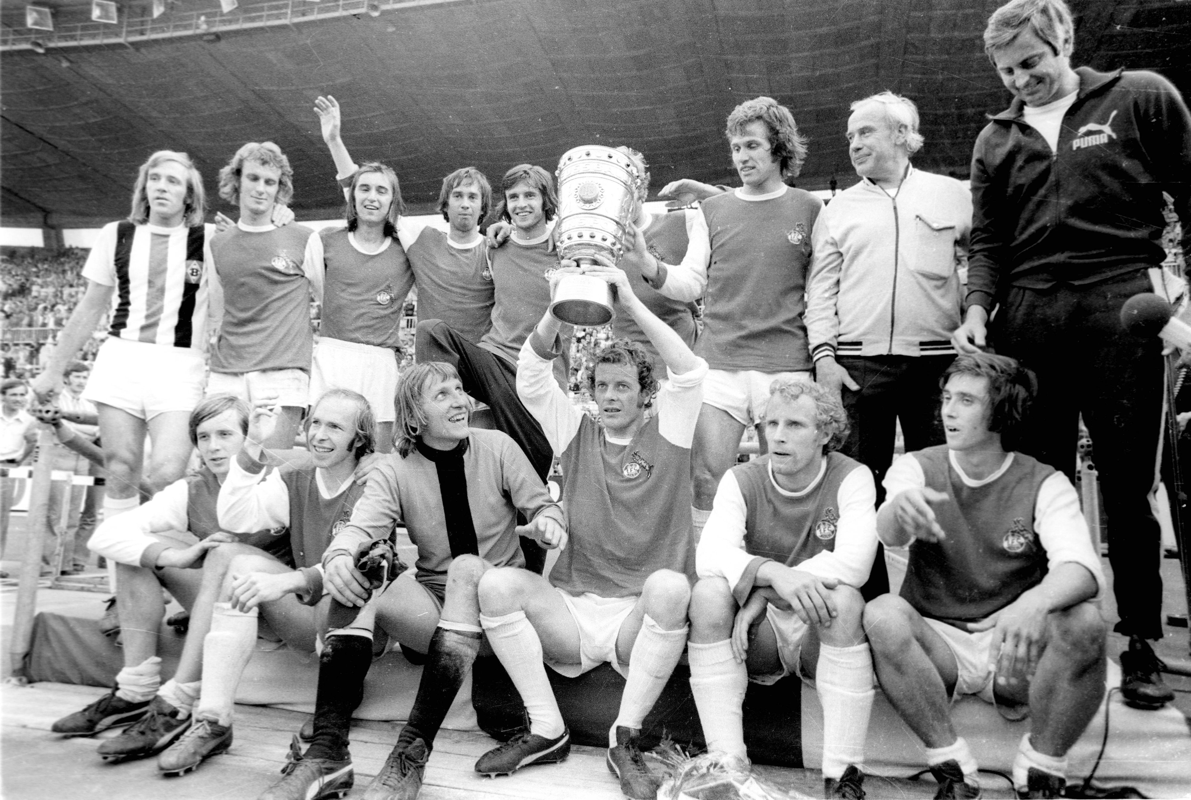 So sehen Pokalhelden und Derbysieger aus! Die Spieler von Borussia Mönchengladbach feiern mit Trainer Hennes Weisweiler 1973 im Düsseldorfer Rheinstadion den Finaltriumph im DFB-Pokal gegen den 1. FC Köln. Herbert Wimmer zeigt dabei stolz die Trophäe.
