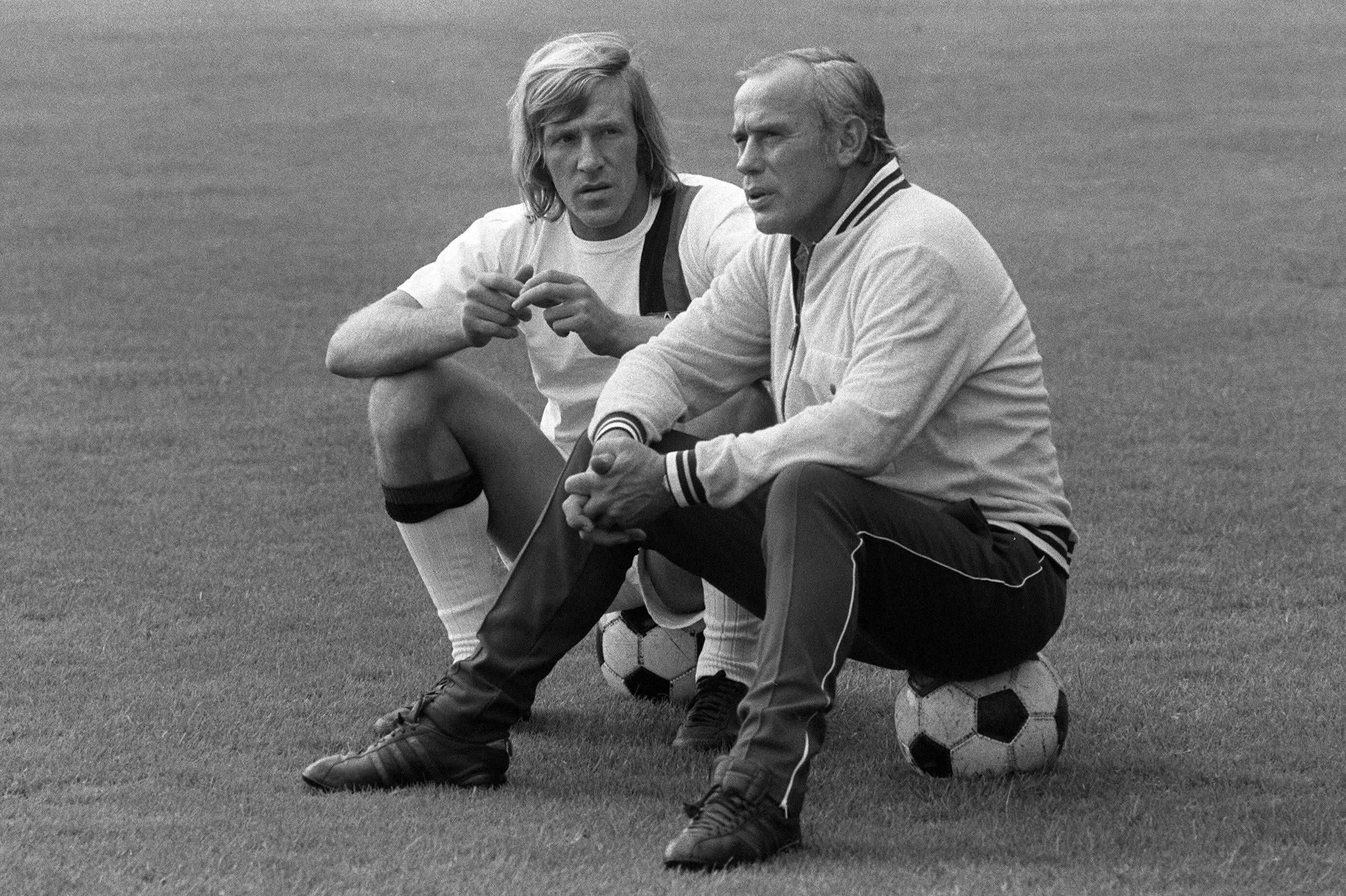 Hennes Weisweiler (r.), Trainer-Legende von Borussia Mönchengladbach, im Gespräch mit seinem Spielmacher Günter Netzer (l.). Dieses Foto zeigt die beiden am 25. Juli 1971. Die beiden sitzen jeweils auf einem Fußball.
