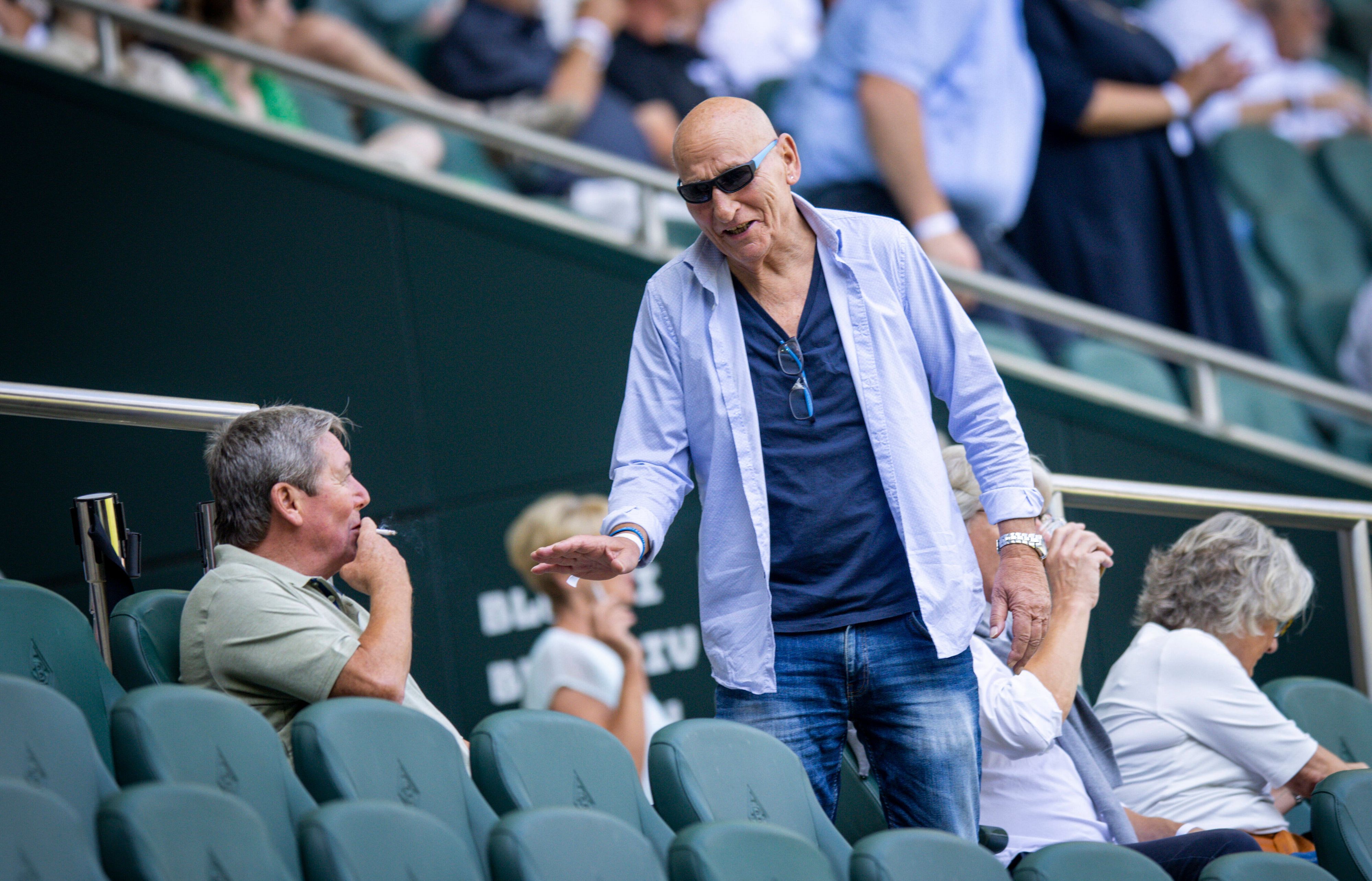 Wolfgang Kleff, Torwart-Legende von Borussia Mönchengladbach, begrüßt auf der Tribüne im Borussia-Park den bis dato letzten Titel-Trainer im Fohlen-Stall, Bernd Krauss. Das Foto zeigt die beiden am 23. Juli 2022. Kleff trägt eine Sonnenbrille. Krauss zieht an einer Zigarette.