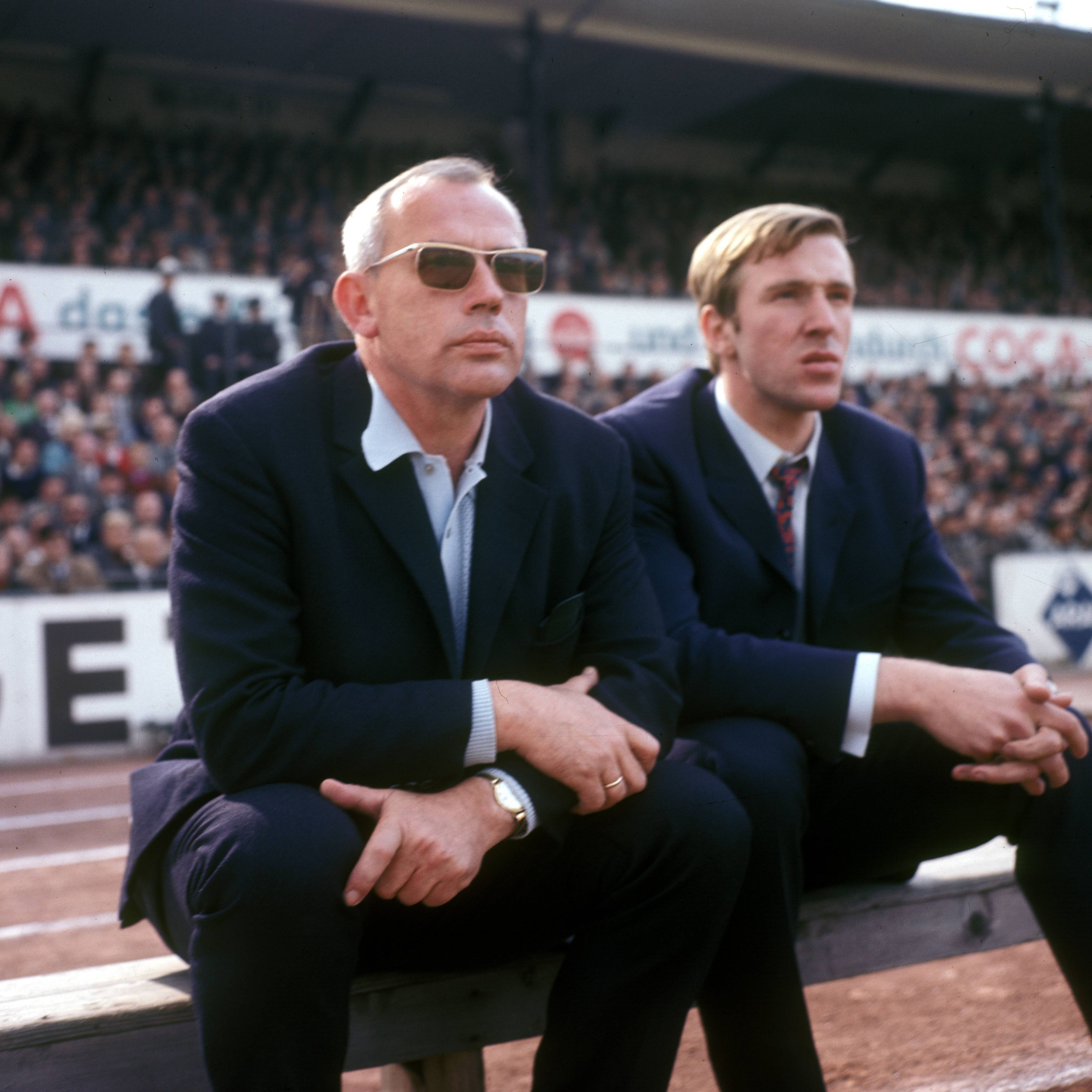 Hennes Weisweiler (l.), verstorbener Legenden-Trainer von Borussia Mönchengladbach, hier gemeinsam mit Fohlen-Spielmacher Günter Netzer. Das Foto ist am 1. September 1968 entstanden.  Die beiden sitzen auf der Bank und schauen auf das Spielfeld.