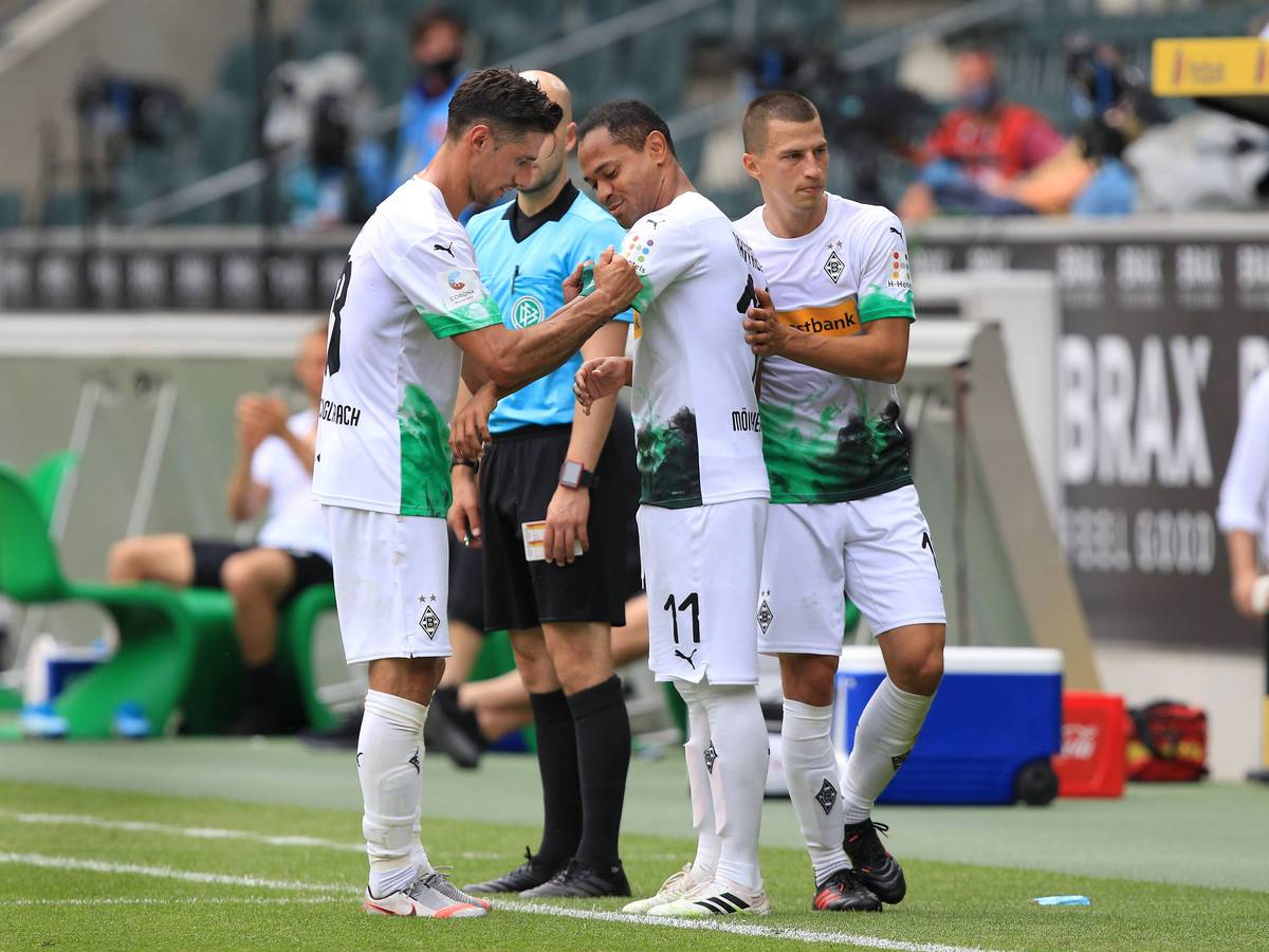 Lars Stindl (l.) überreicht Raffael (M.) in dessen letztem Spiel für Borussia Mönchengladbach gegen Hertha BSC am 27. Juni 2020 die Kapitänsbinde.