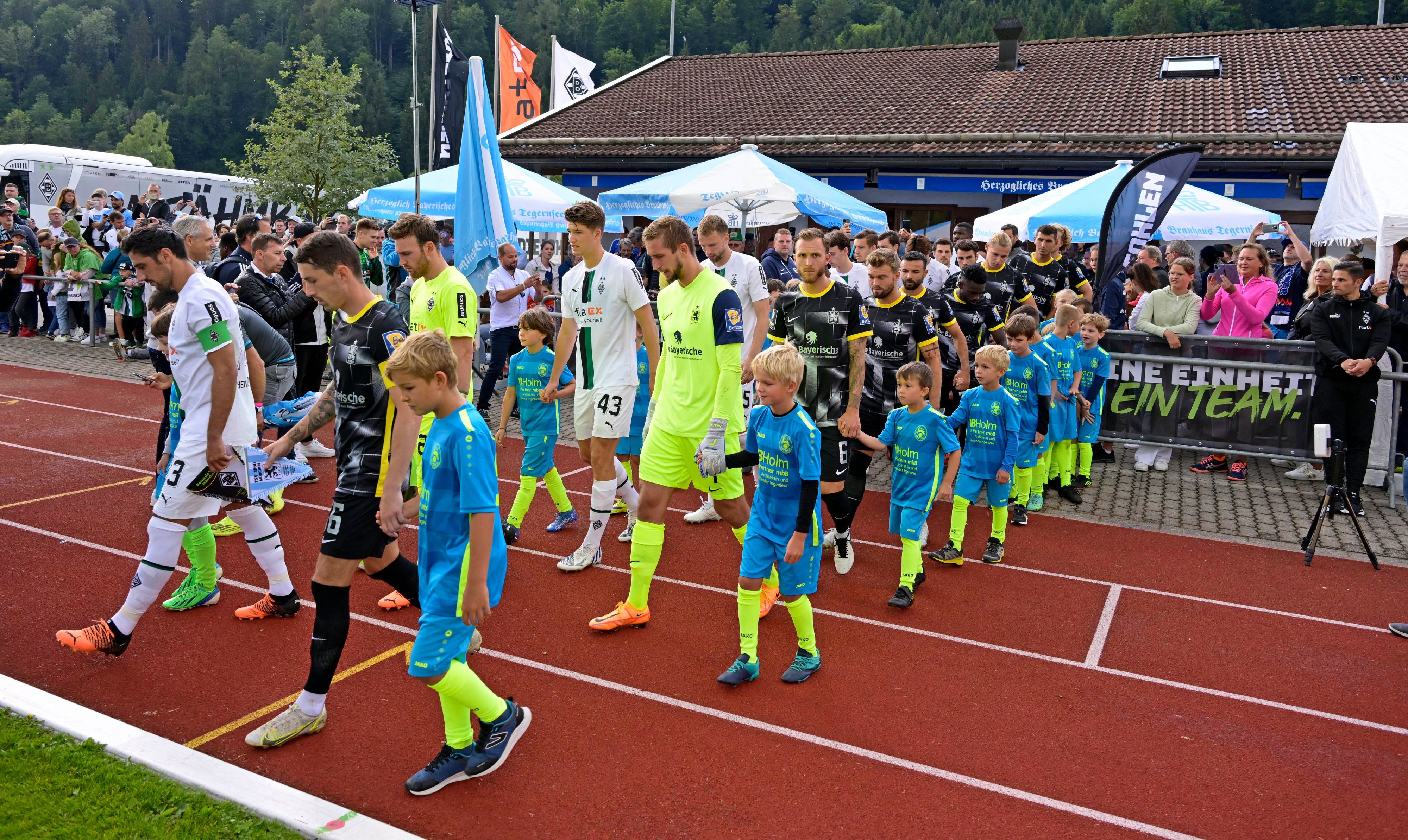 Auch in dieser Sommervorbereitung trägt Borussia Mönchengladbach wieder ein Testspiel auf dem Sportplatz Birkenmoos in Rottach-Egern aus. Das Foto stammt vom letztjährigen Test gegen 1860 München am 10. Juli 2022. Die Teams laufen vor dem Spiel auf das Feld.