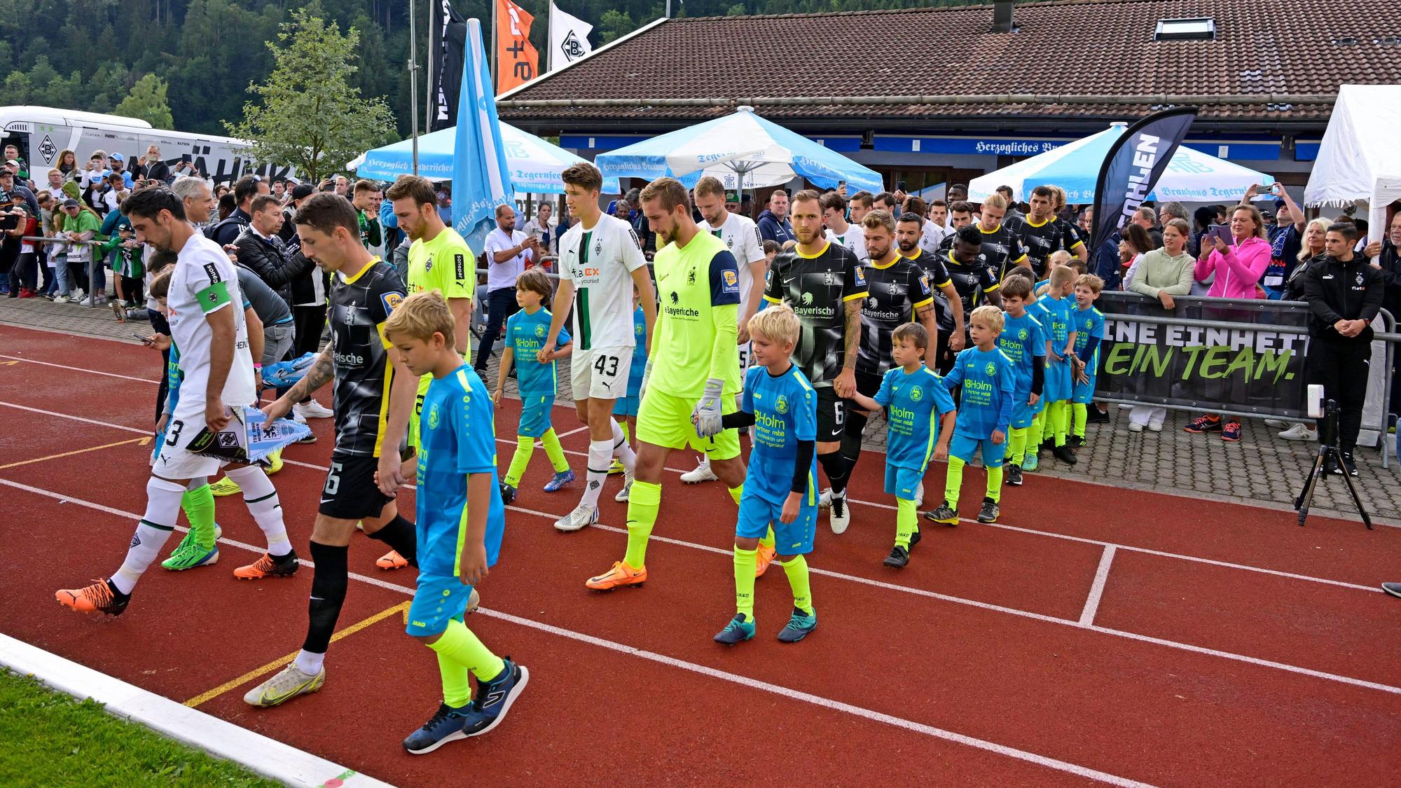 Auch in dieser Sommervorbereitung trägt Borussia Mönchengladbach wieder ein Testspiel auf dem Sportplatz Birkenmoos in Rottach-Egern aus. Das Foto stammt vom letztjährigen Test gegen 1860 München am 10. Juli 2022. Die Teams laufen vor dem Spiel auf das Feld.