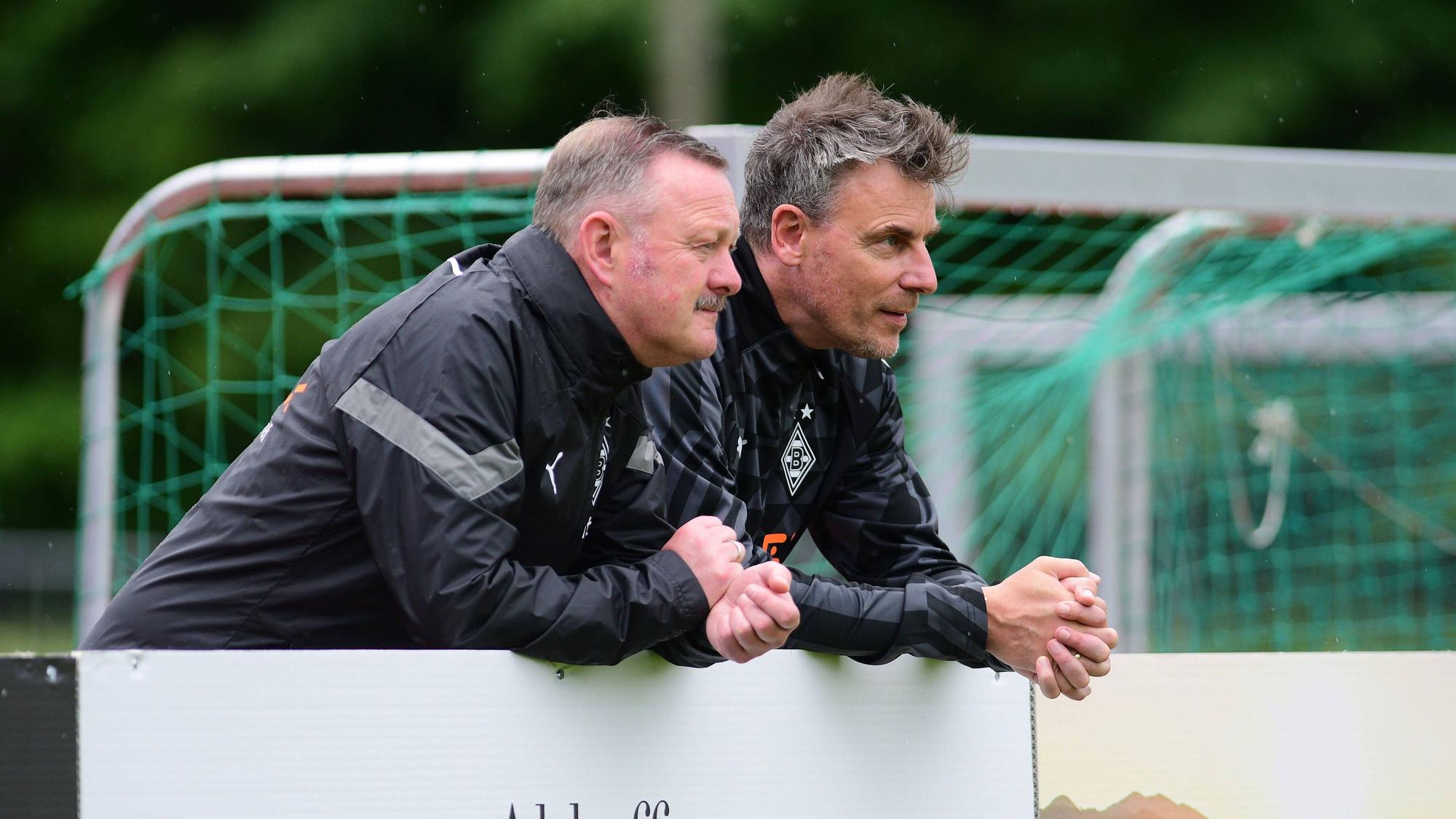 Roland Virkus (l.) und Steffen Korell stehen im Trainingslager von Borussia Mönchengladbach am 4. Juli 2022 am Spielfeldrand.