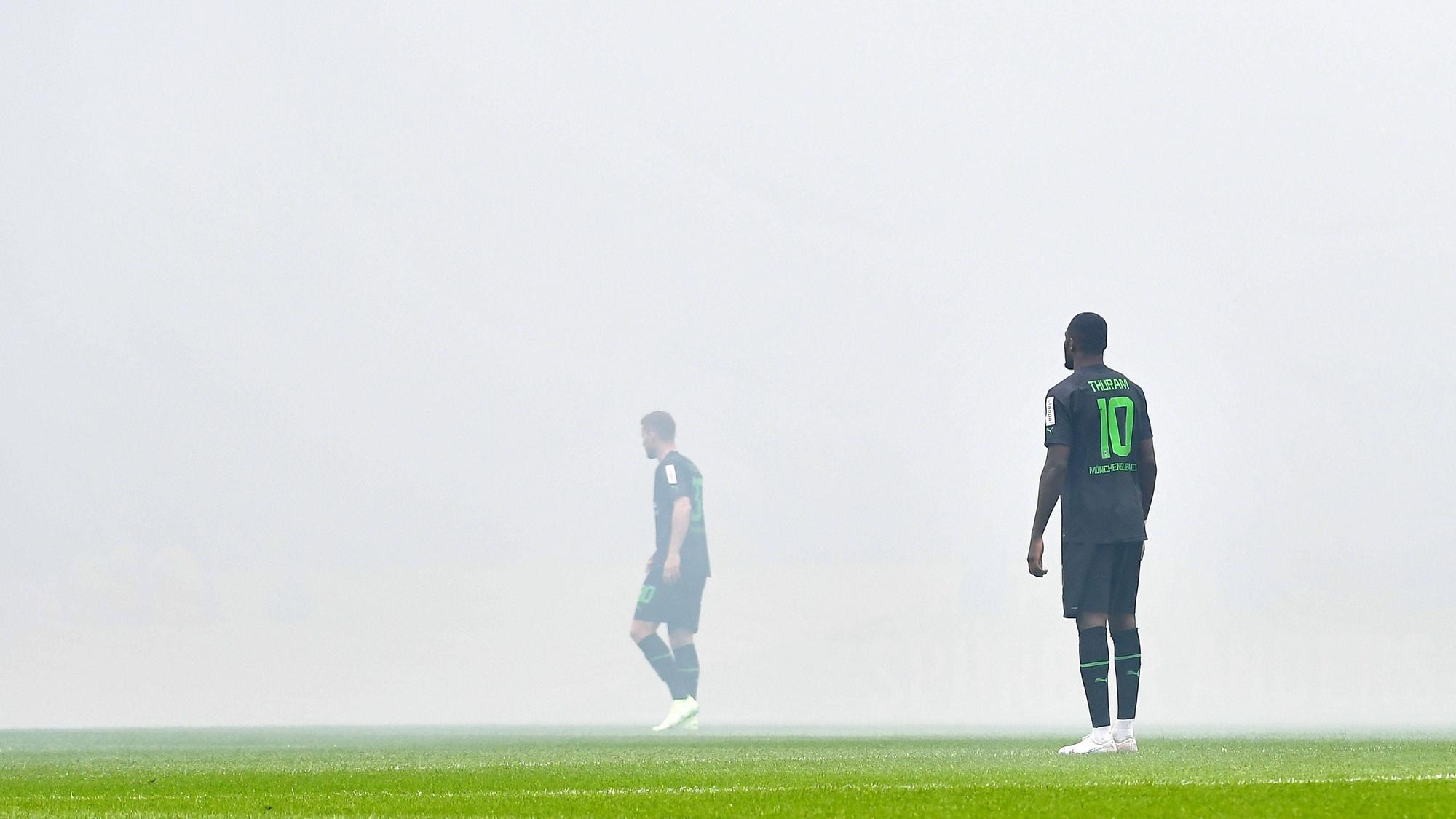 Nico Elvedi (l.) und Marcus Thuram stehen im Pyro-Nebel im Stadion des 1. FC Köln beim Derby am 2. April 2023.