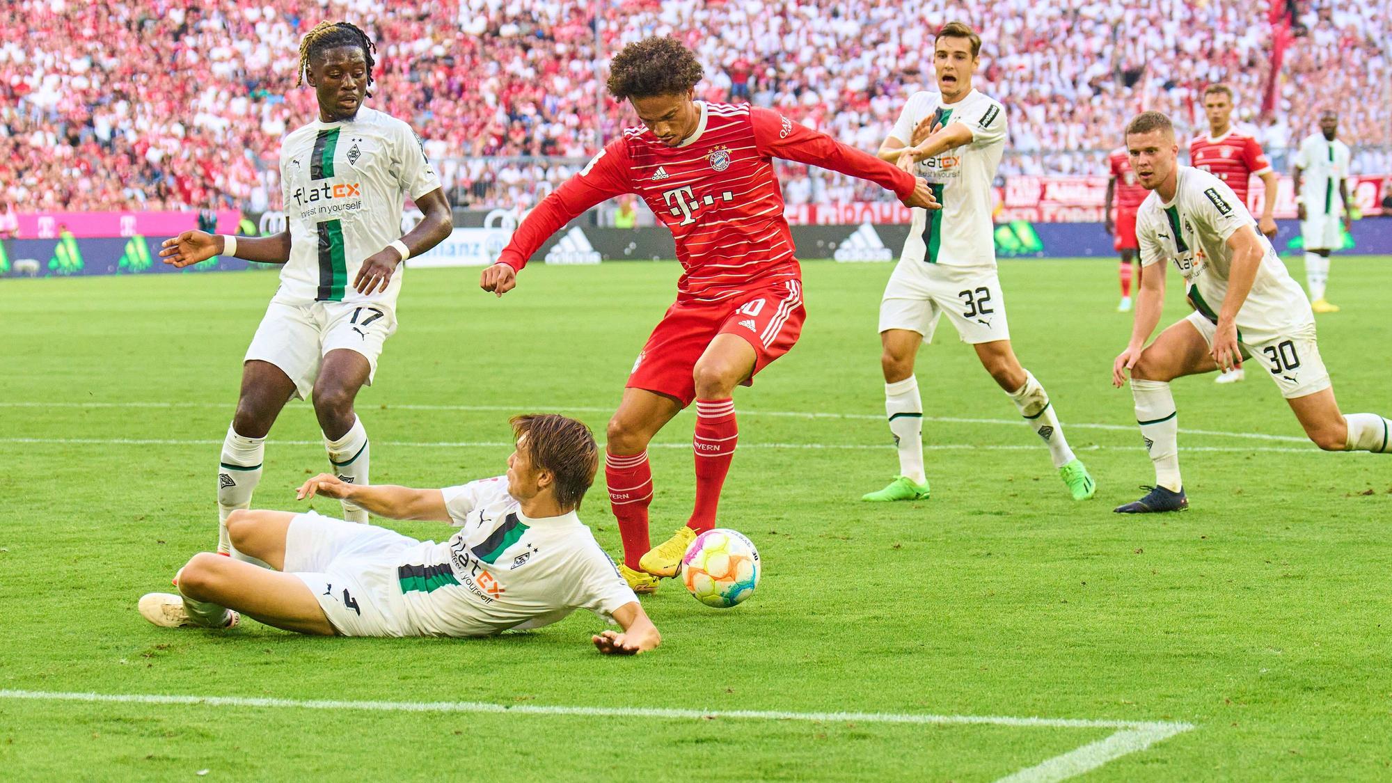Leroy Sané von Bayern München will beim Bundesliga-Spiel gegen Borussia Mönchengladbach am 27. August 2022 schießen, wird aber von Ko Itakura (liegend) geblockt.