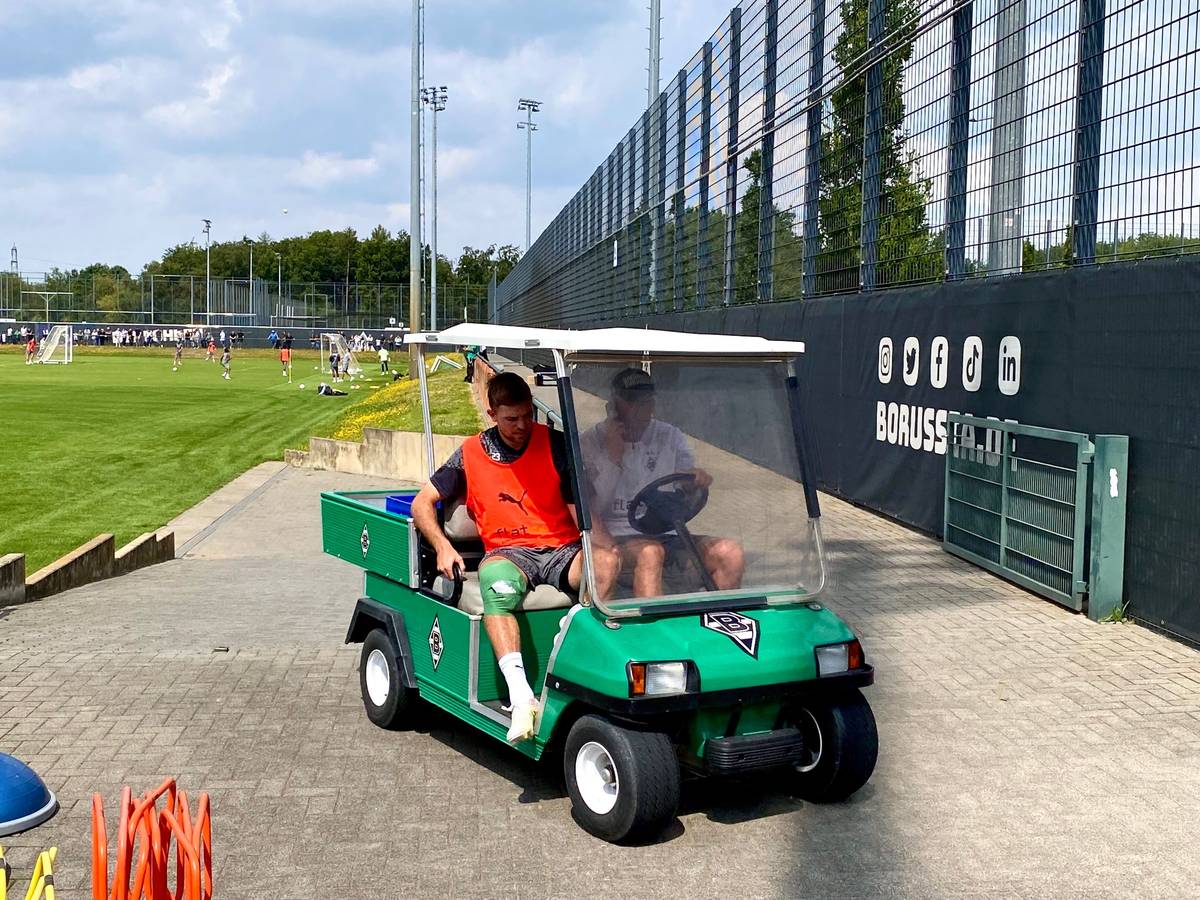 Christoph Kramer (l.) wird am 21. Juli 2023 beim Training von Borussia Mönchengladbach mit einem Golf-Kart vom Platz gefahren. Der Weltmeister hat sich am rechten Knie verletzt, das dick bandagiert ist.