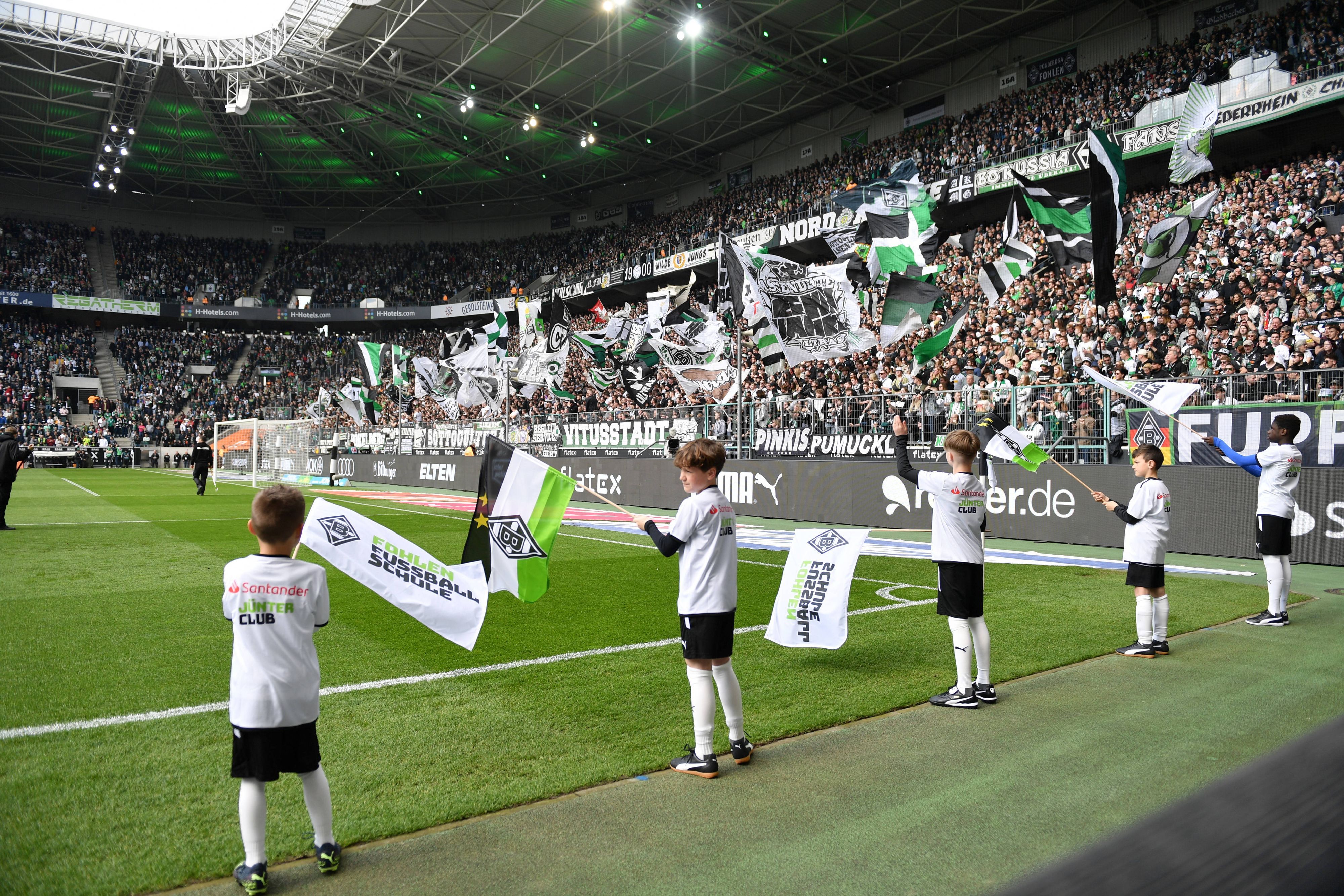 Der Borussia-Park vor einem Heimspiel von Borussia Mönchengladbach am 9. April 2023 – dazu schwenken Kinder an der Seitenauslinie Gladbach-Fahnen.
