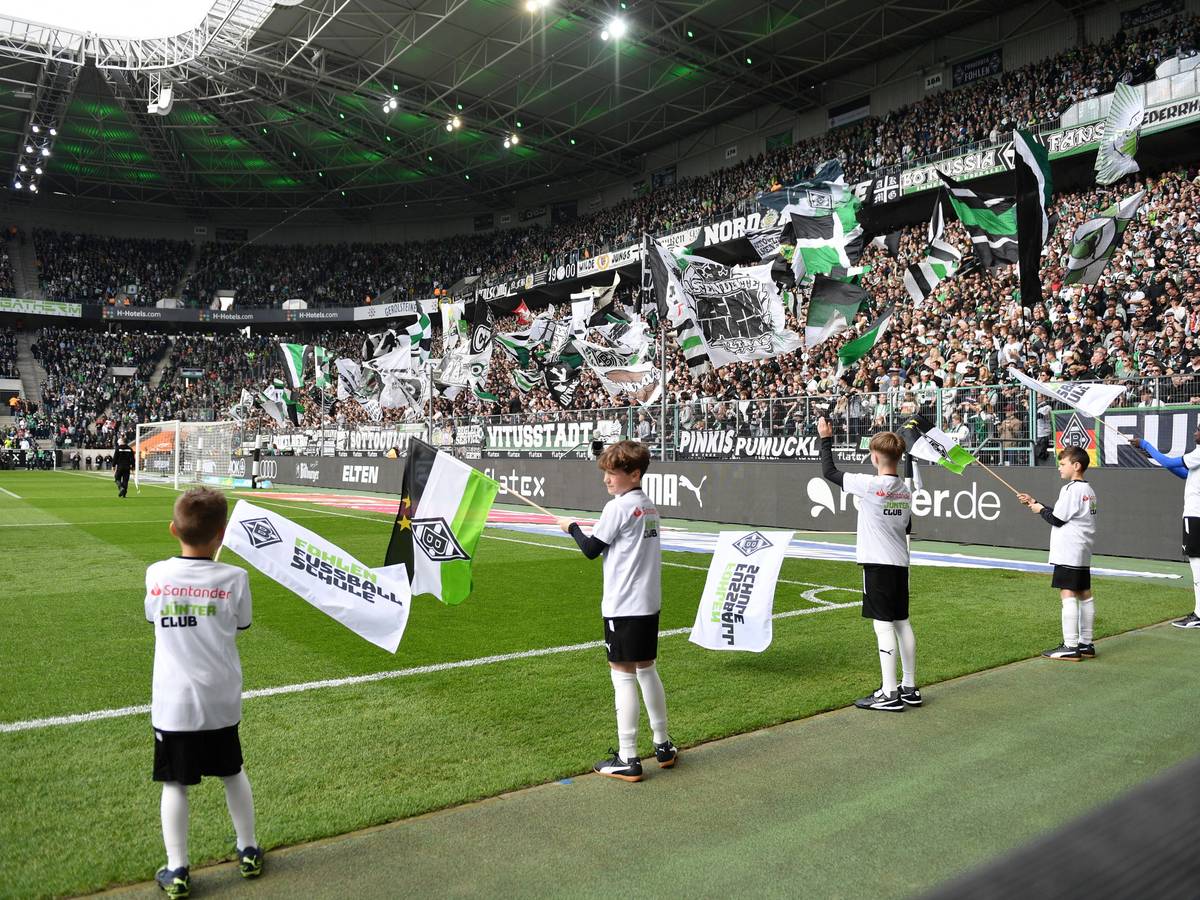 Der Borussia-Park vor einem Heimspiel von Borussia Mönchengladbach am 9. April 2023 – dazu schwenken Kinder an der Seitenauslinie Gladbach-Fahnen.