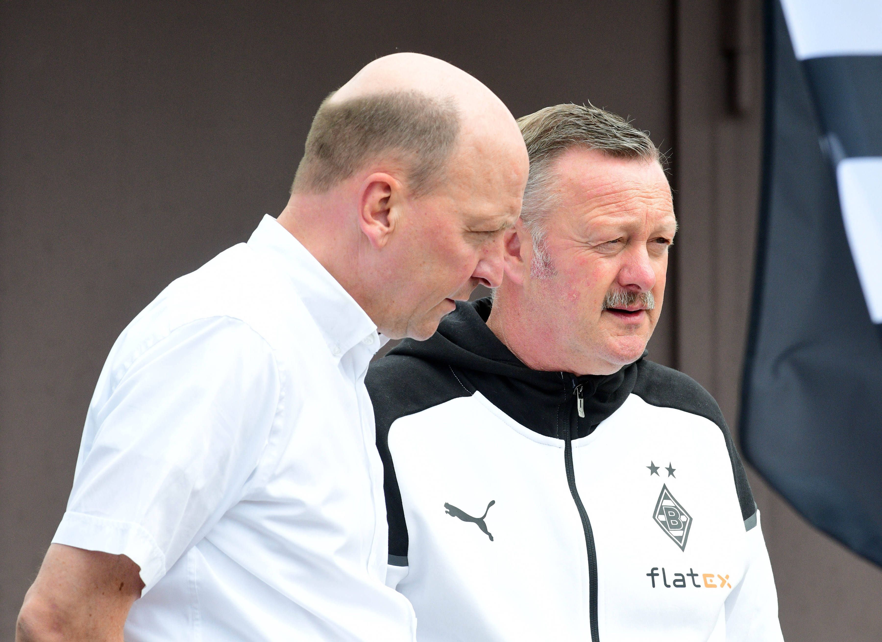 Entscheider unter sich: Finanz-Boss Stephan Schippers (l.) tauscht sich am Rande des Fohlen-Trainings in Rottach-Egern mit Gladbach-Manager Roland Virkus (r.) aus. Das Foto zeigt die beidem am 25. Juli 2023 auf der Sportanlage Birkenmoos. Virkus spricht, Schippers hört zu und schaut Richtung Boden.
