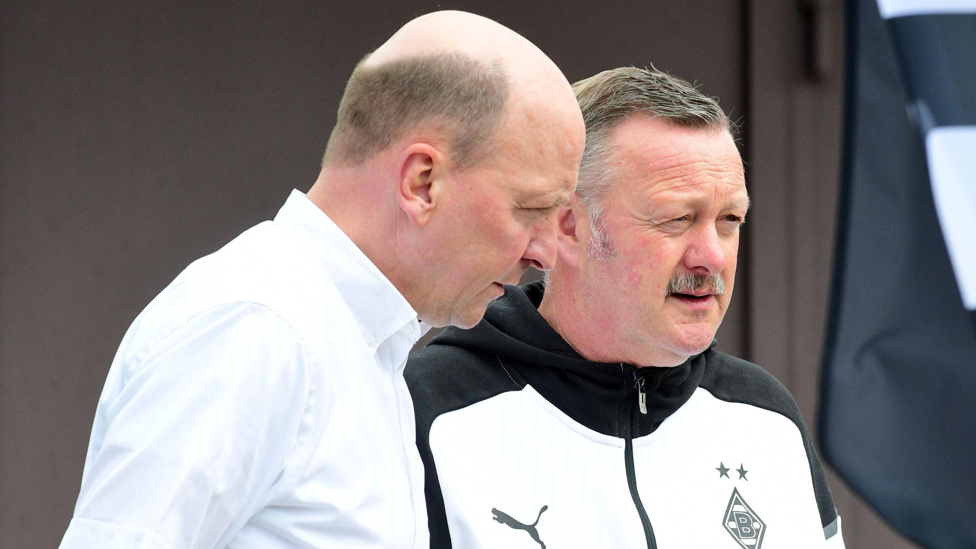 Entscheider unter sich: Finanz-Boss Stephan Schippers (l.) tauscht sich am Rande des Fohlen-Trainings in Rottach-Egern mit Gladbach-Manager Roland Virkus (r.) aus. Das Foto zeigt die beidem am 25. Juli 2023 auf der Sportanlage Birkenmoos. Virkus spricht, Schippers hört zu und schaut Richtung Boden.