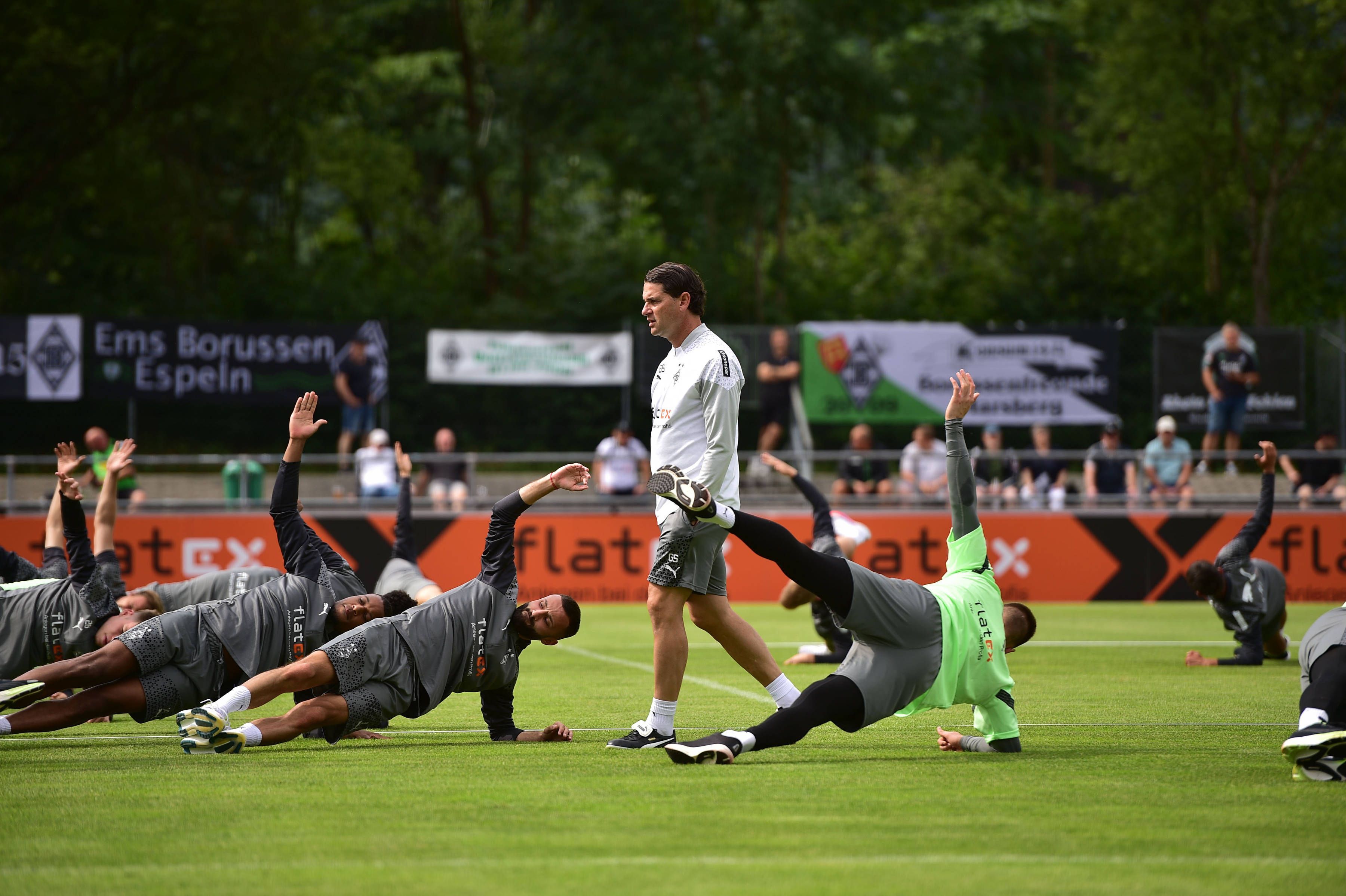 Gerardo Seoane steht bei einem Training von Borussia Mönchengladbach am 24. Juli 2023, während seine Spieler auf dem Rasen Stabilitäts-Übungen machen.