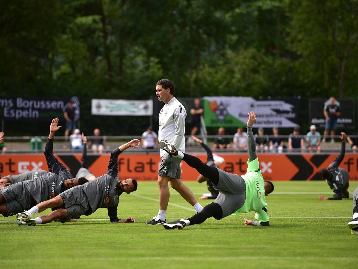 Gerardo Seoane steht bei einem Training von Borussia Mönchengladbach am 24. Juli 2023, während seine Spieler auf dem Rasen Stabilitäts-Übungen machen.