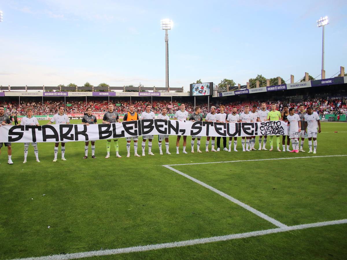 Die Mannschaft von Borussia Mönchengladbach hält ein Banner mit der Aufschrift „Stark bleiben, Stevie!“. Das Foto stammt vom 11. August 2023, im Anschluss an das DFB-Pokalspiel beim TuS Bersenbrück in Osnabrück.
