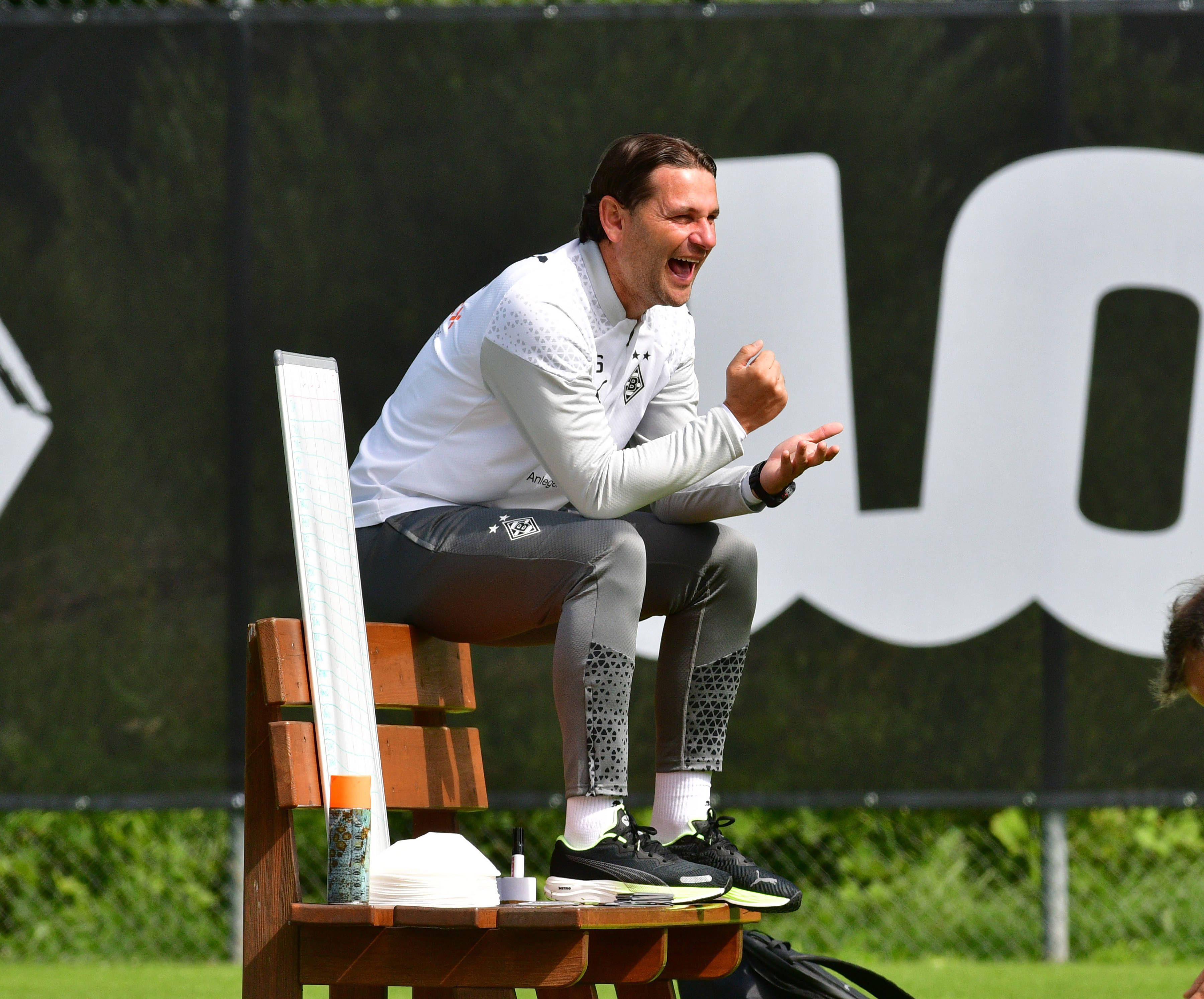 Gerardo Seoane sitzt im Trainingslager am 27. August auf einer Bank und lacht.