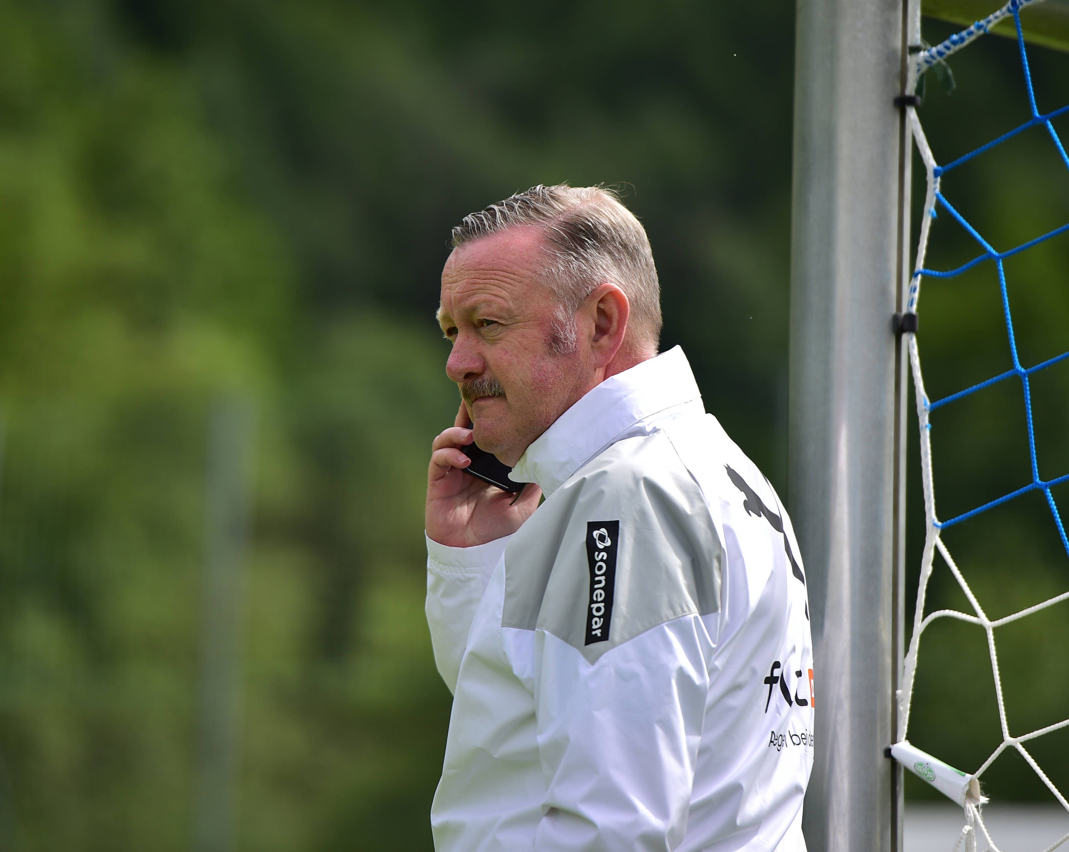 Roland Virkus hält im Trainingslager von Borussia Mönchengladbach am 27. Juli 2023 ein Handy am Ohr.