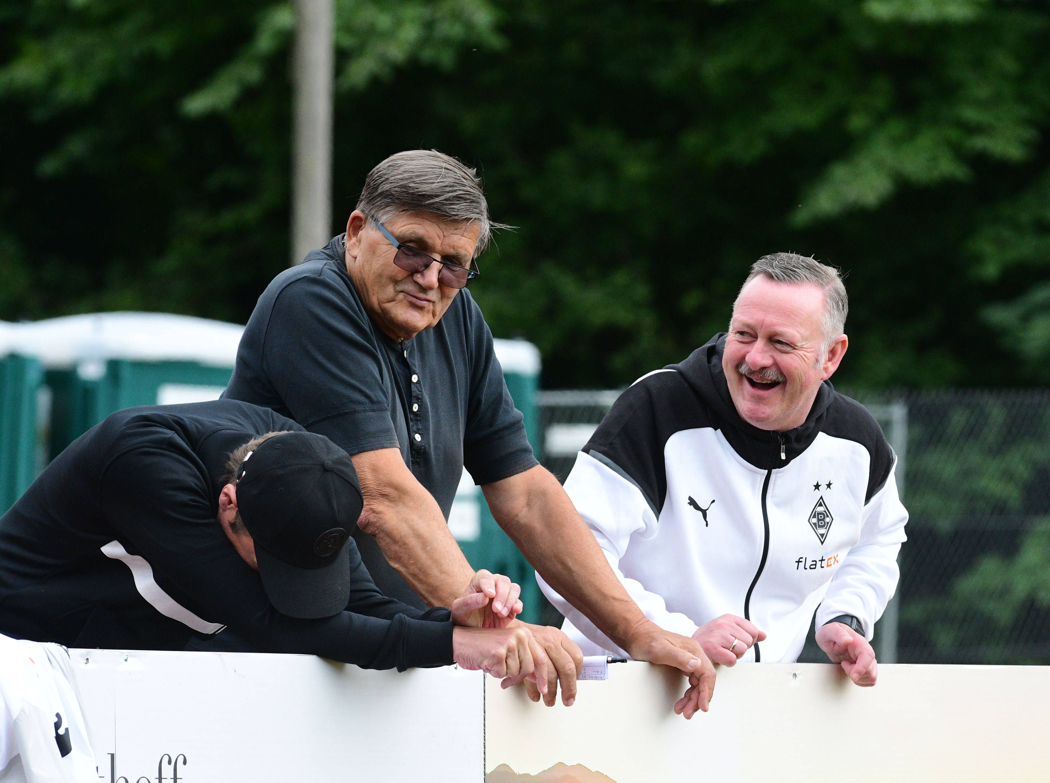 Roland Virkus (r.) bringt Präsidiumsmitglied Hans Meyer (M.) und Stadionsprecher Torsten Knippertz im Trainingslager von Borussia Mönchengladbach am 25. Juli 2023 zum Lachen.