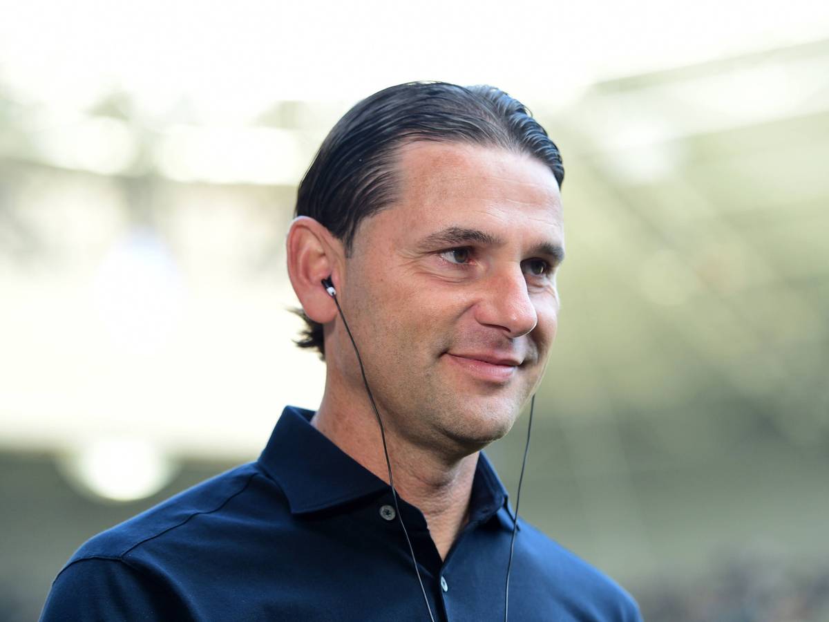 Gerardo Seoane, Trainer von Borussia Mönchengladbach, hier am 26. August 2023 im Interview vor dem Bundesliga-Spiel gegen Bayer Leverkusen, mit Kopfhörern im Ohr, seelig lächelnd.