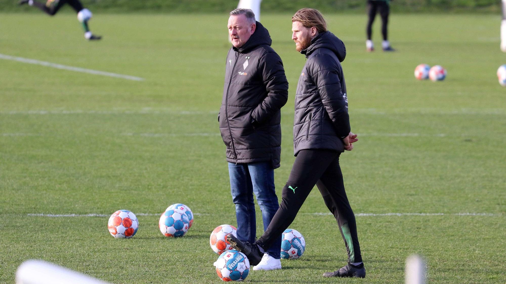 Roland Virkus (l.) und Eugen Polanski beobachten eine Trainings-Einheit am 15. Februar 2022.