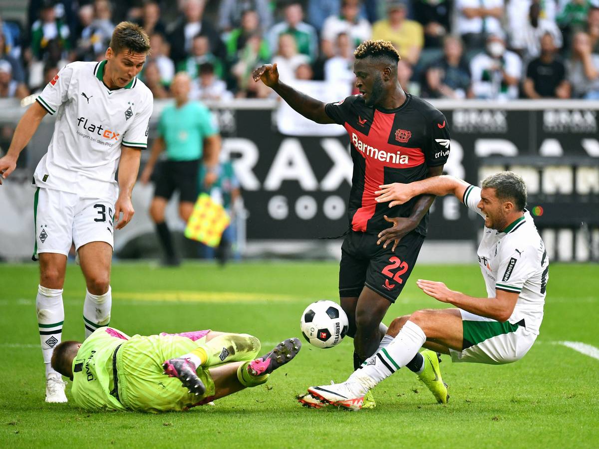 Drei Spieler von Borussia Mönchengladbach strecken sich am 26. August 2023, um Victor Boniface (Nummer 22) von Bayer Leverkusen beim Schuss zu stören.