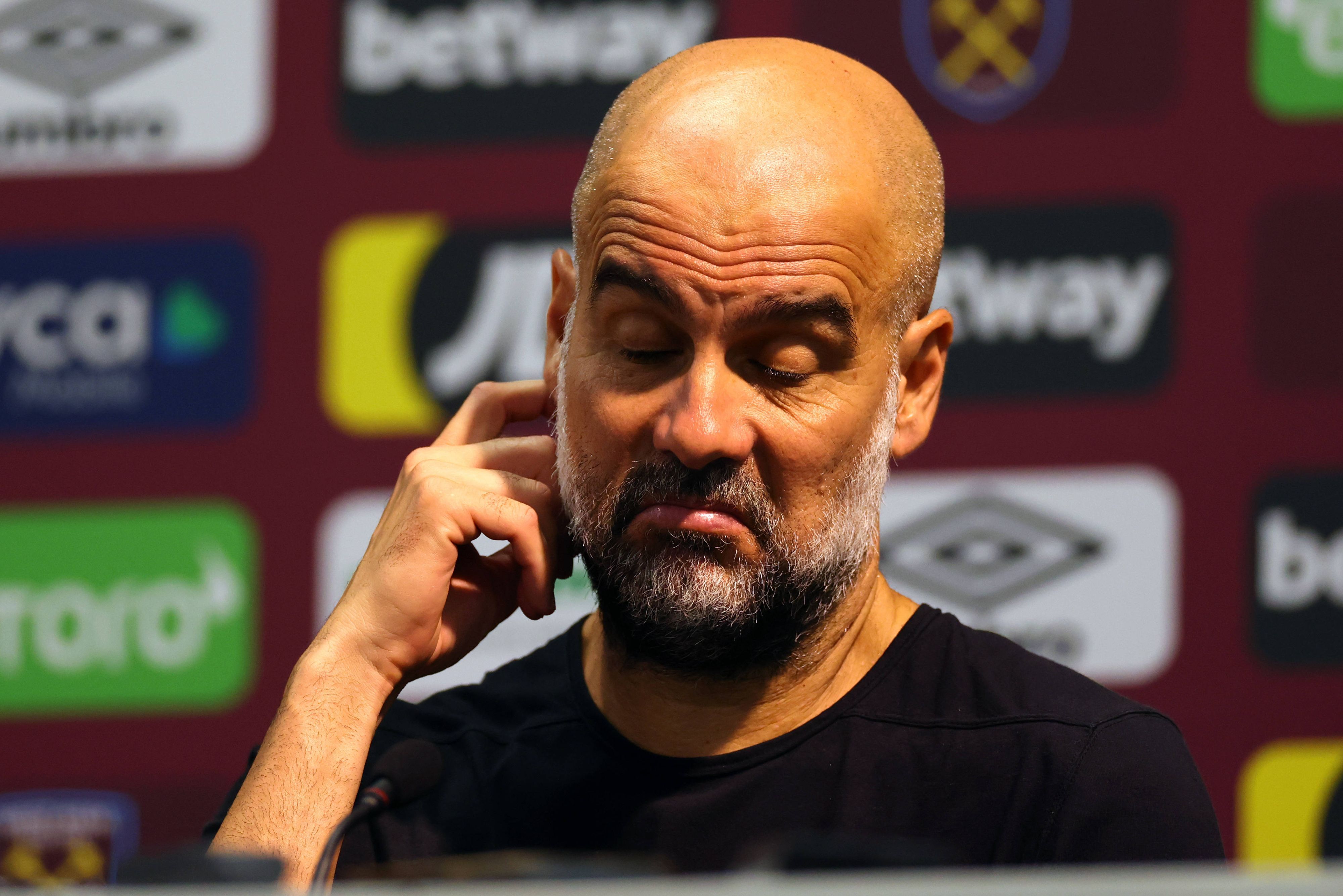 Pep Guardiola kratzt sich bei einer Pressekonferenz am 16. September 2023 am rechten Ohr.