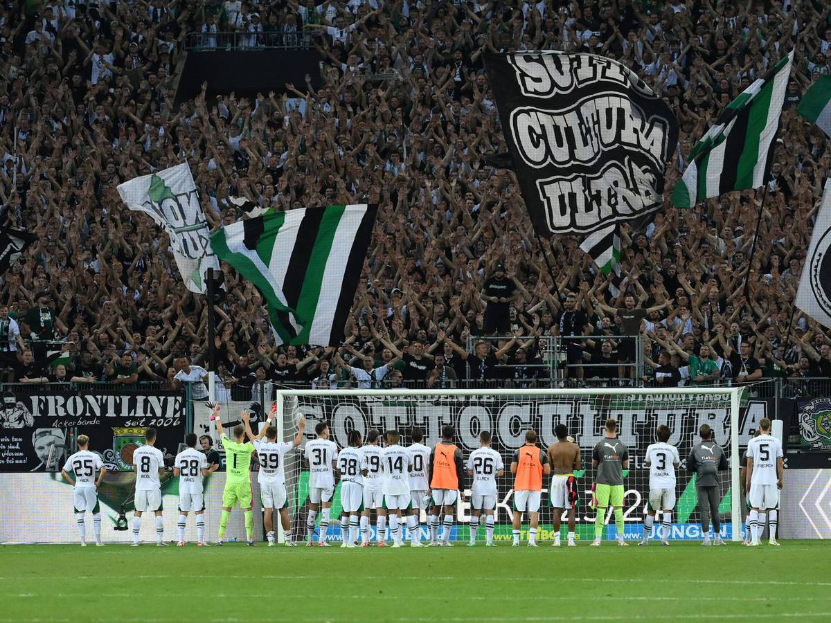 Die Gladbach-Spieler stehen nebeneinander vor ihren Fans in der Nordkurve. Die Fans jubeln und schwenken Fahnen.