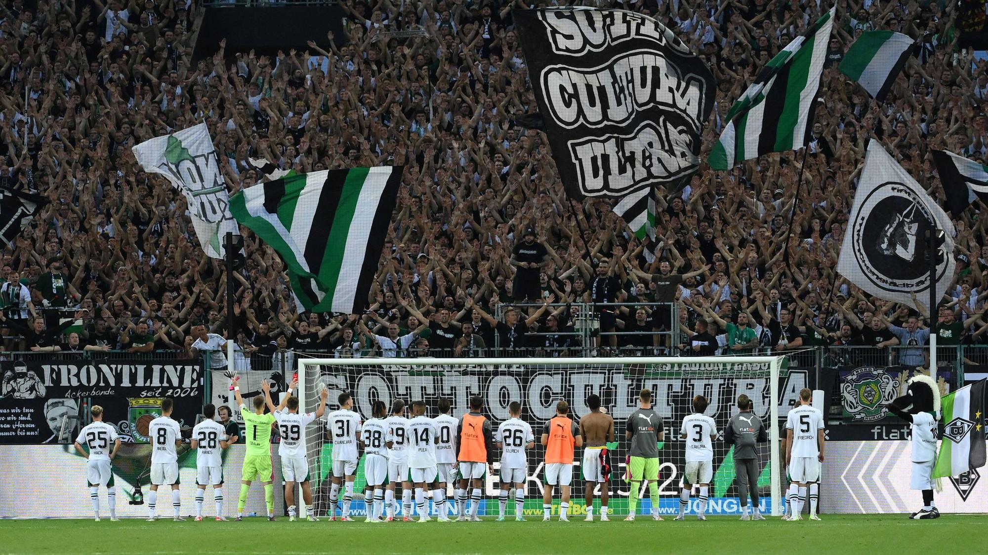 Die Gladbach-Spieler stehen nebeneinander vor ihren Fans in der Nordkurve. Die Fans jubeln und schwenken Fahnen.