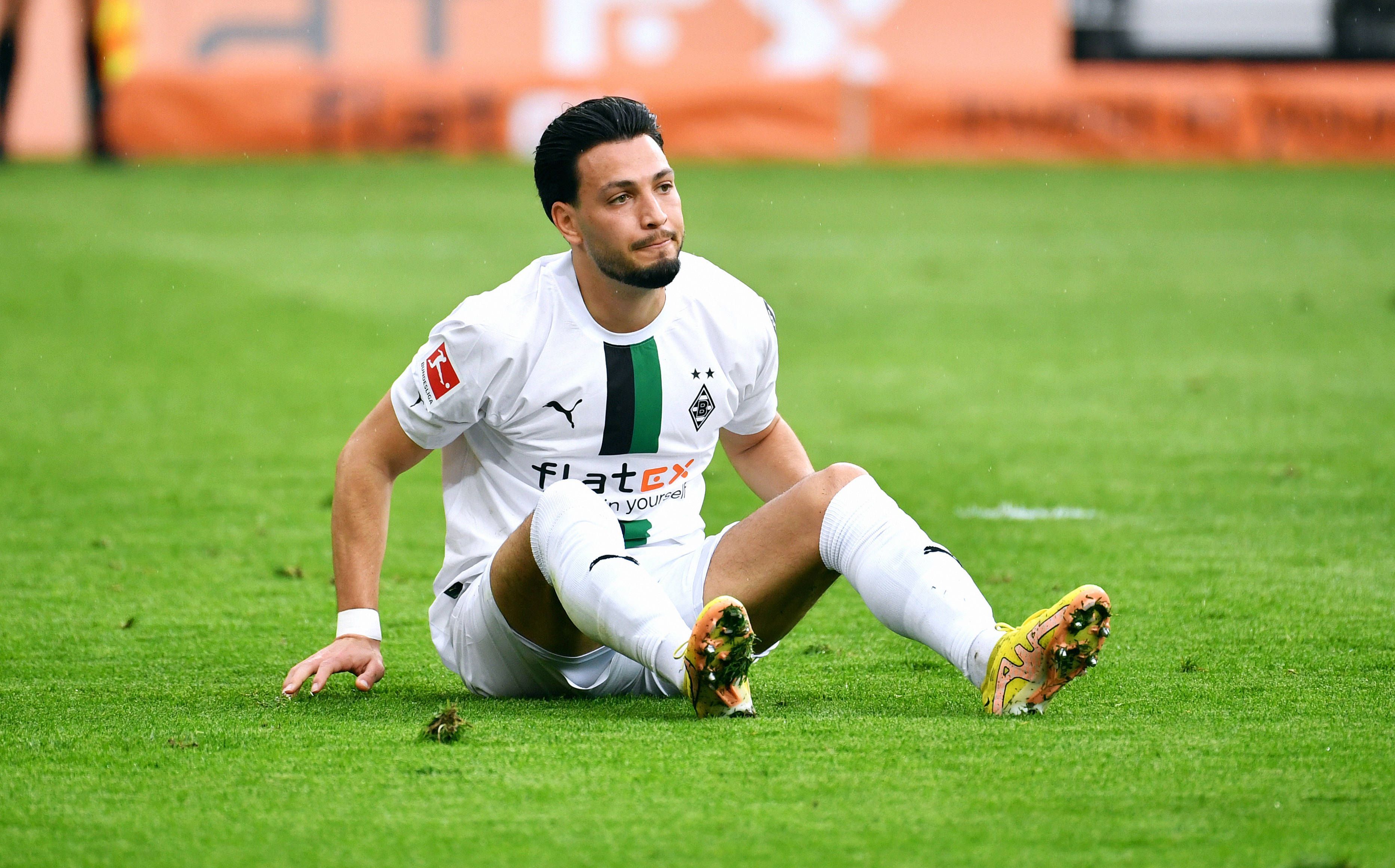 Ramy Bensebaini sitzt auf dem Boden.