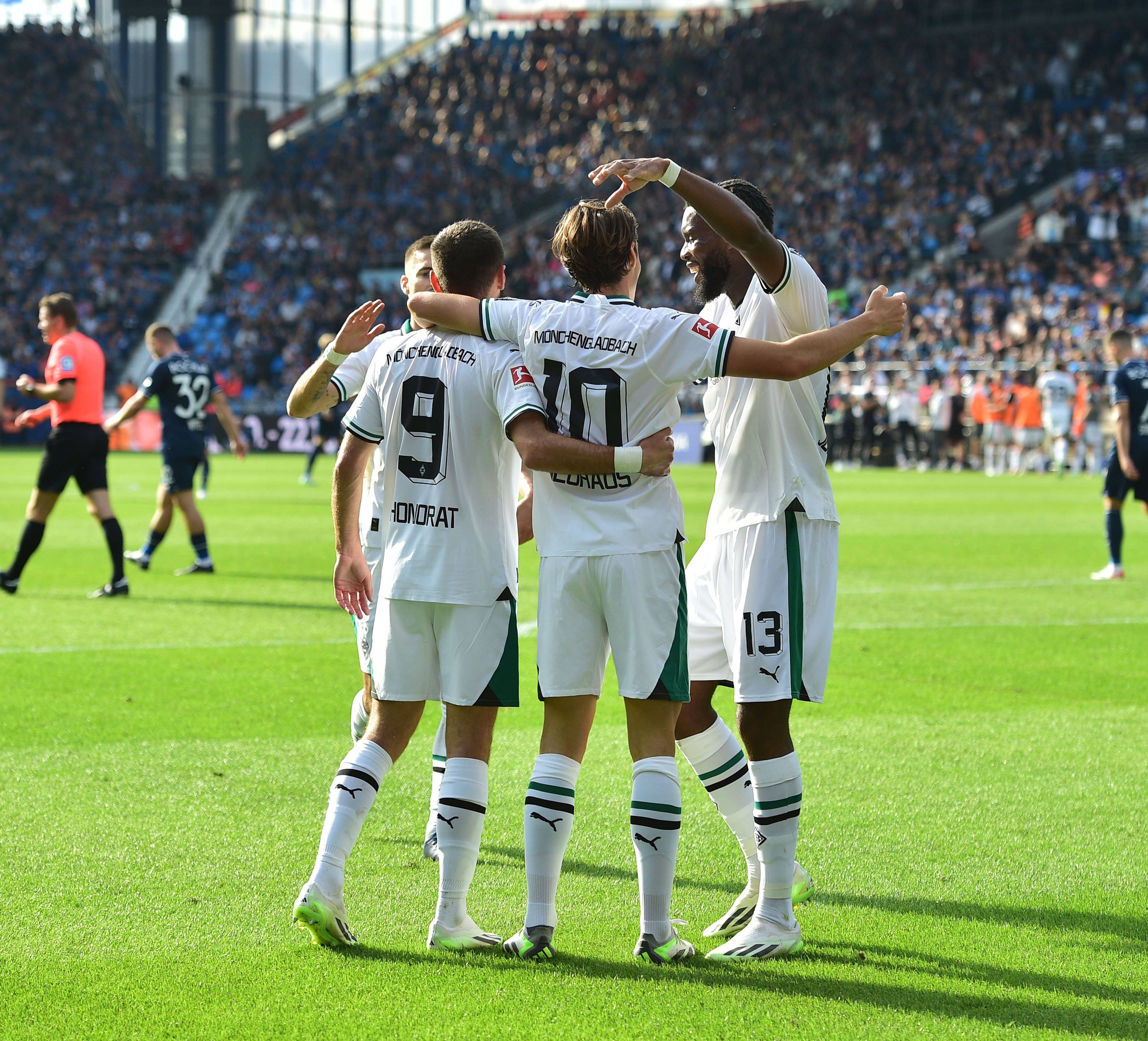 Gladbach-Spieler laufen aufeinander zu, umarmen sich und jubeln.