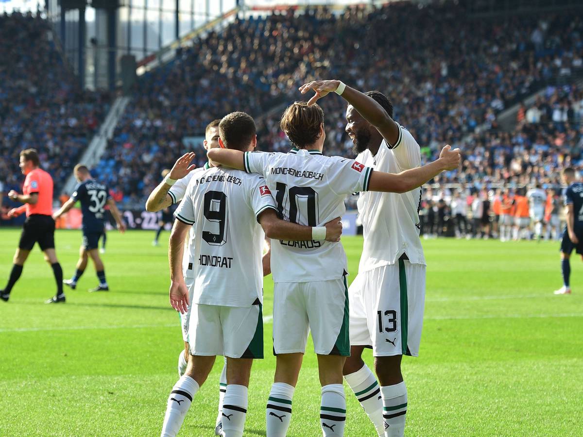 Gladbach-Spieler laufen aufeinander zu, umarmen sich und jubeln.