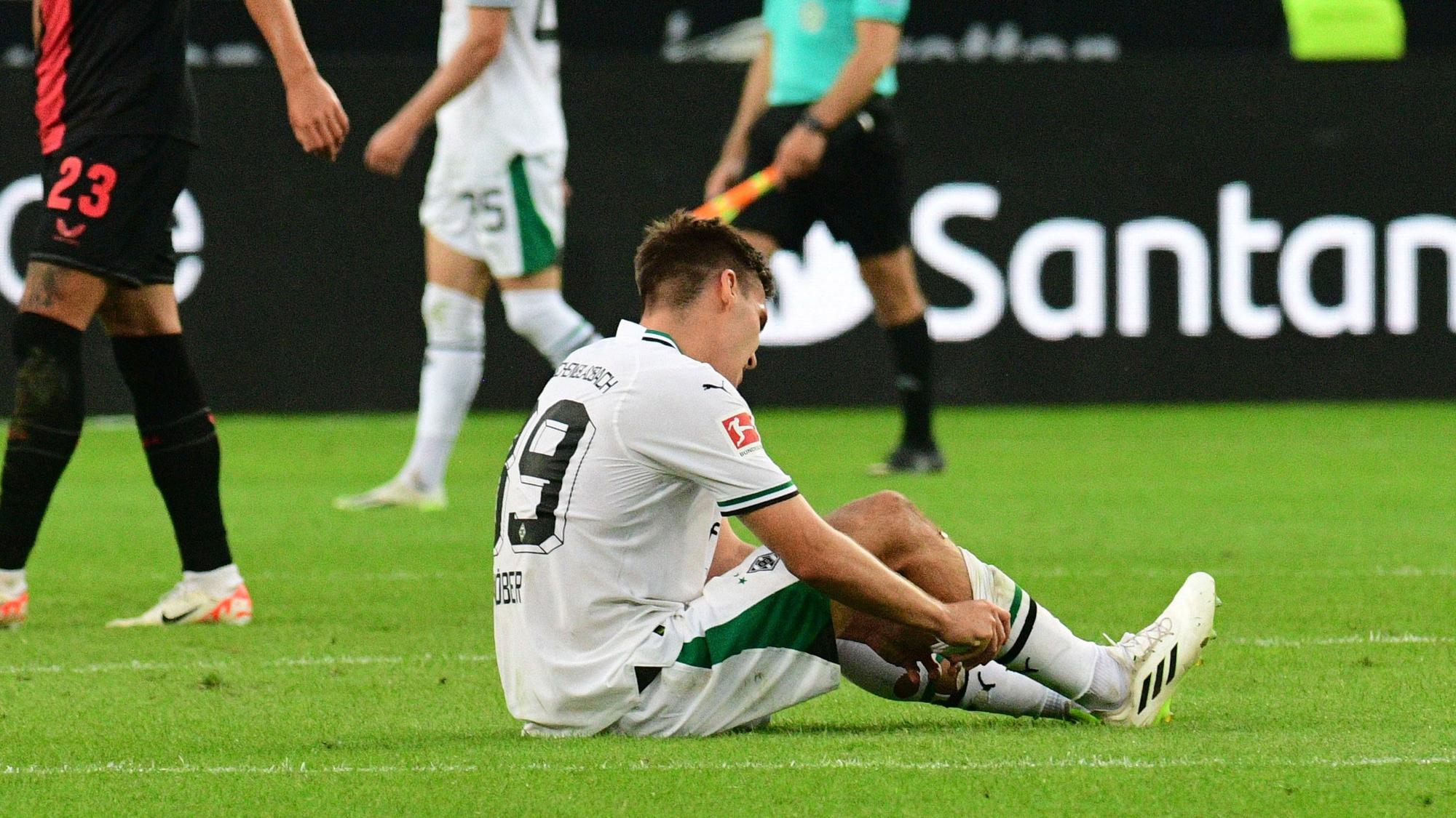 Max Wöber von Borussia Mönchengladbach sitzt enttäuscht am Boden nach dem Spiel gegen Bayer Leverkusen am 26. August 2023.