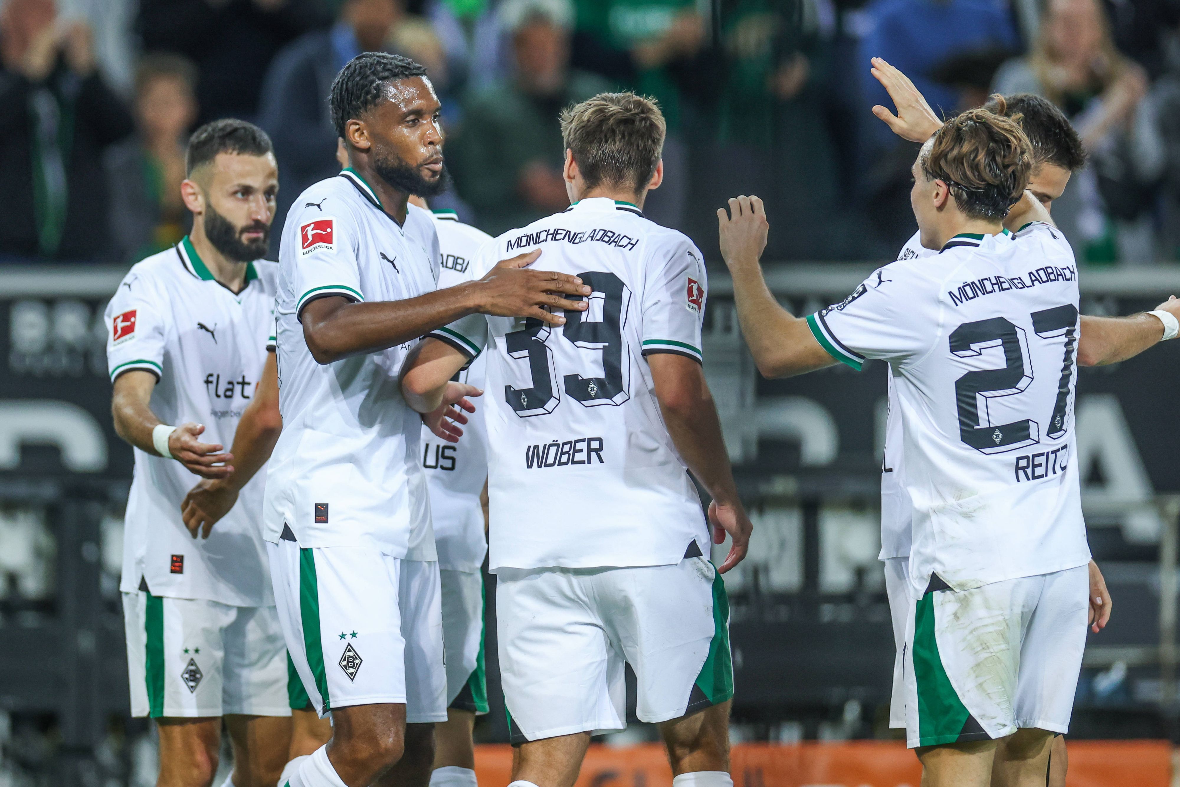 Die Gladbach-Spieler kommen zusammen und bejubeln ein Tor. Im Hintergrund sind Fans.