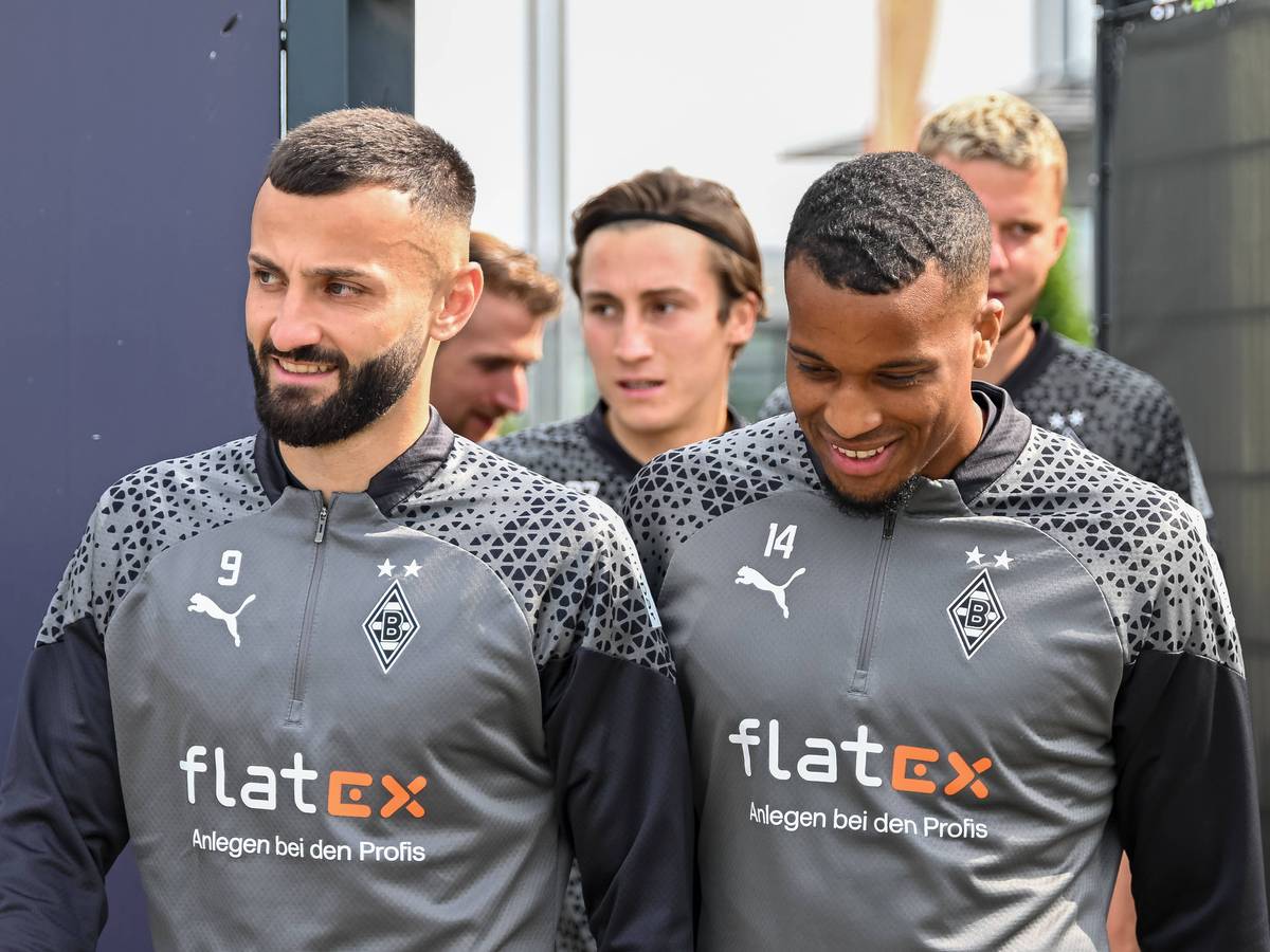 Die Spieler Honorat und Plea gehen gemeinsam auf den Trainingsplatz. Im Hintergrund sind ihre Mitspieler.