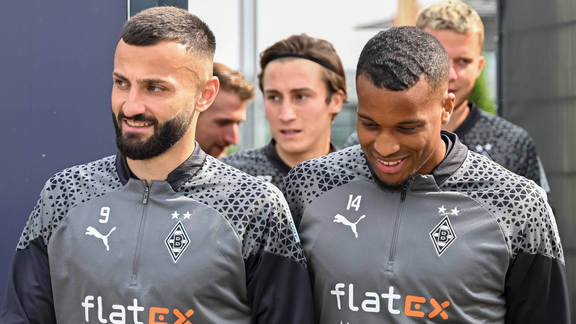 Die Spieler Honorat und Plea gehen gemeinsam auf den Trainingsplatz. Im Hintergrund sind ihre Mitspieler.