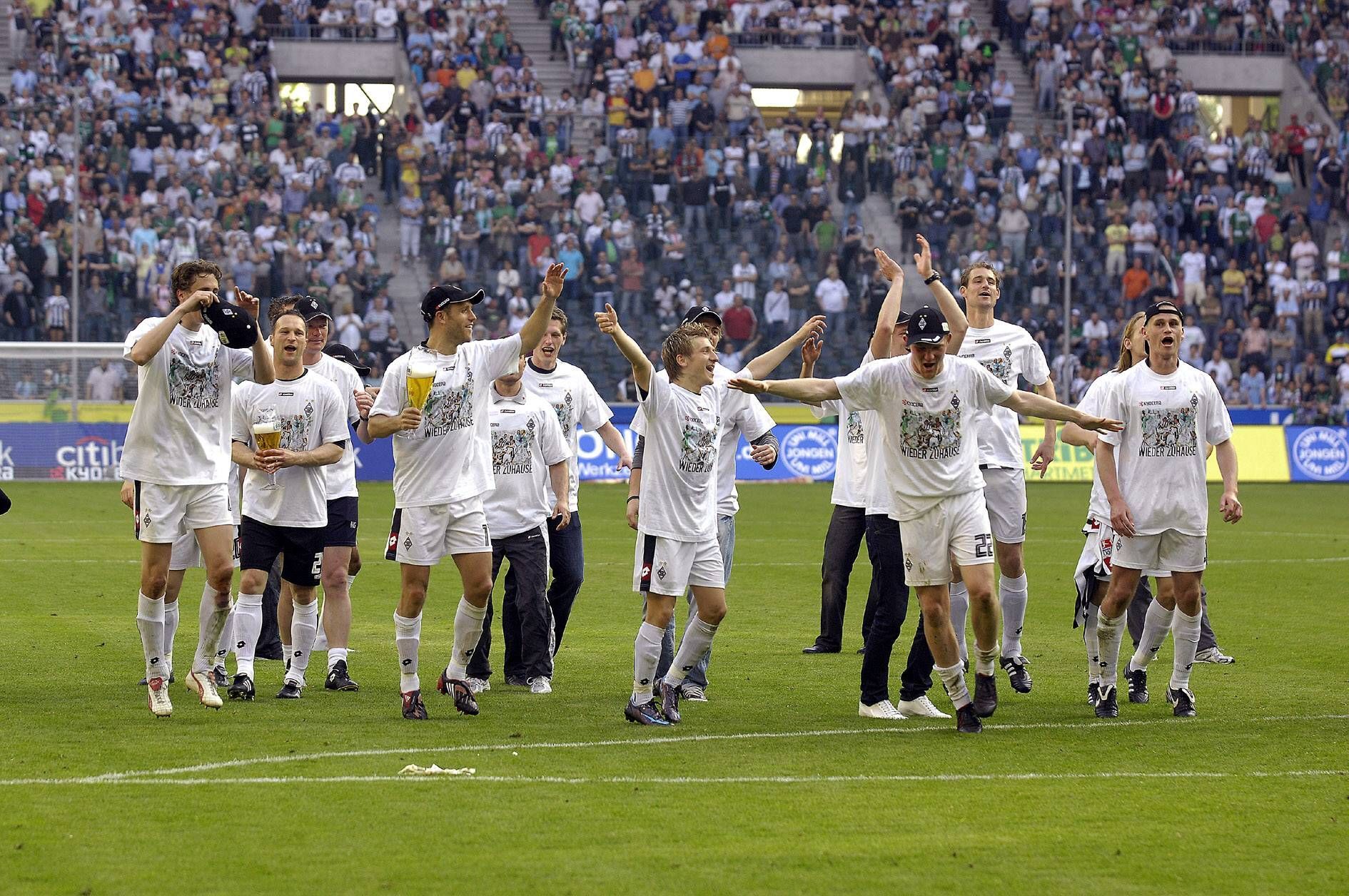 Gladbach Spieler feiern und tanzen zusammen auf dem Platz. Im Hintergrund sind die Fans.