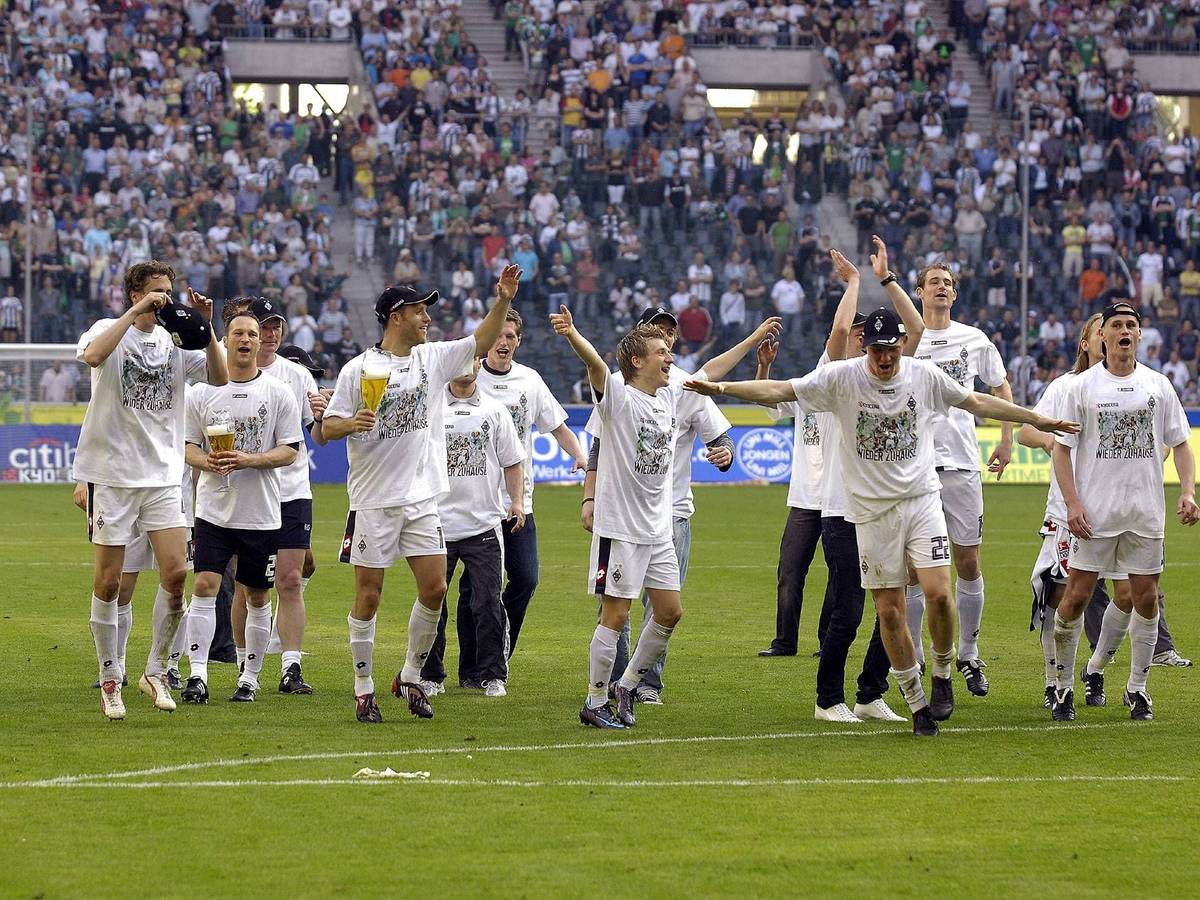 Gladbach Spieler feiern und tanzen zusammen auf dem Platz. Im Hintergrund sind die Fans.