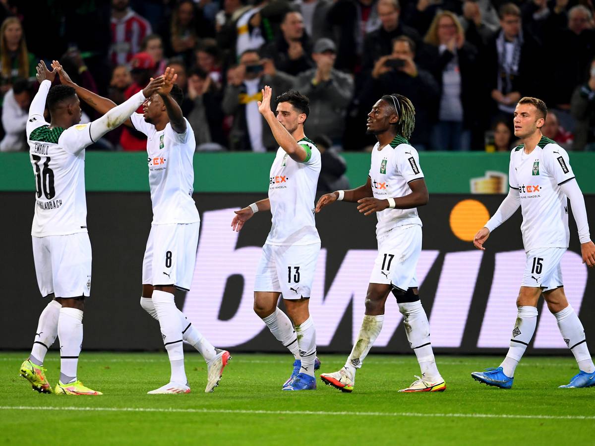 Die Spieler von Borussia klatschen sich nach einem Tor gegenseitig ab. Im Hintergrund feiern die Fans.