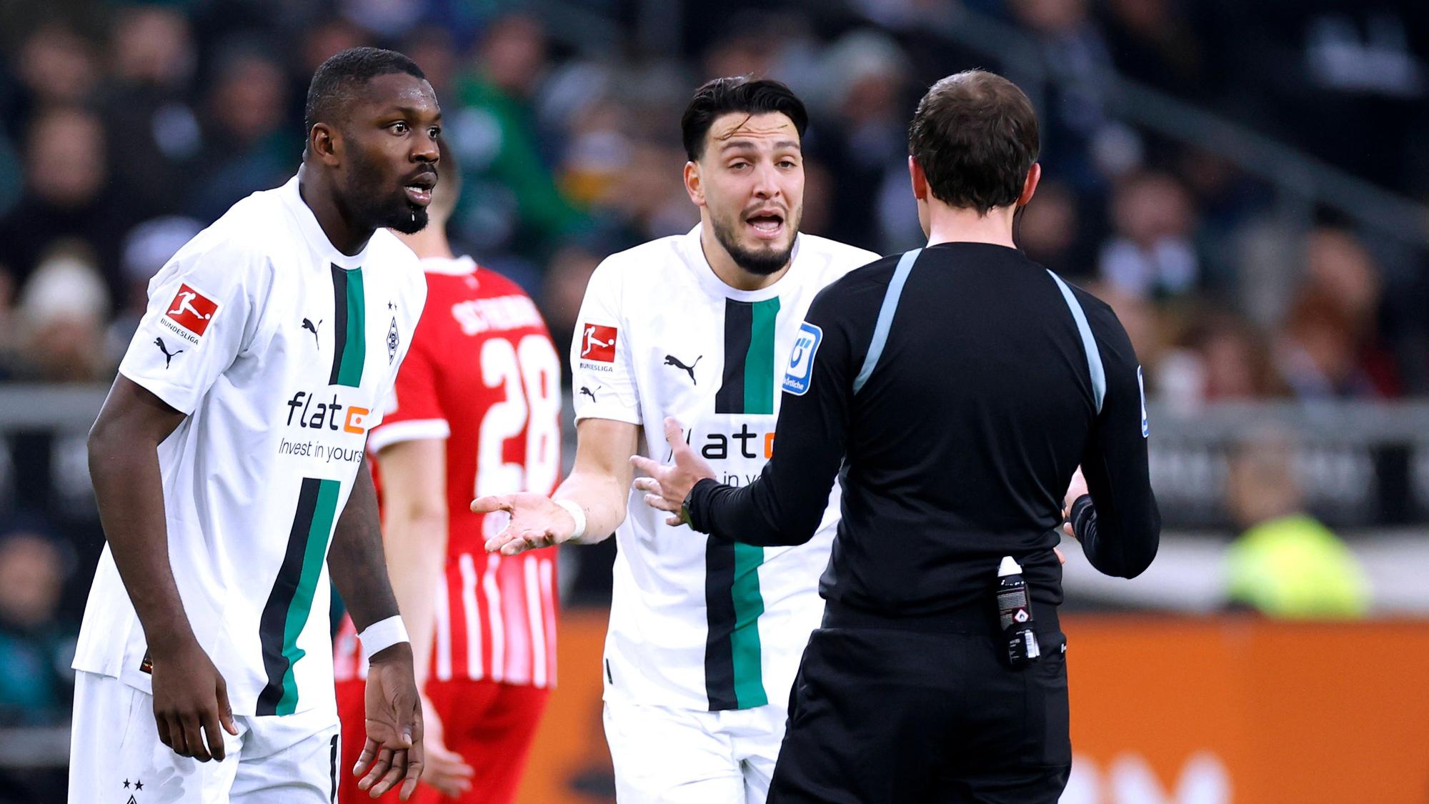 Marcus Thuram und Ramy Bensebaini diskutieren mit dem Schiedsrichter.