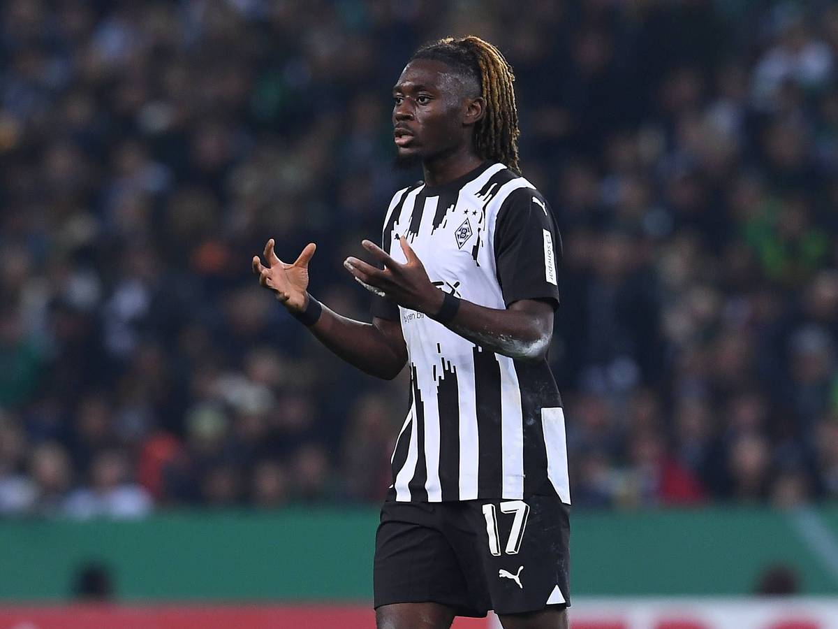 Manu Koné reißt bei einem Borussia-Spiel beide Arme vor seinen Körper.