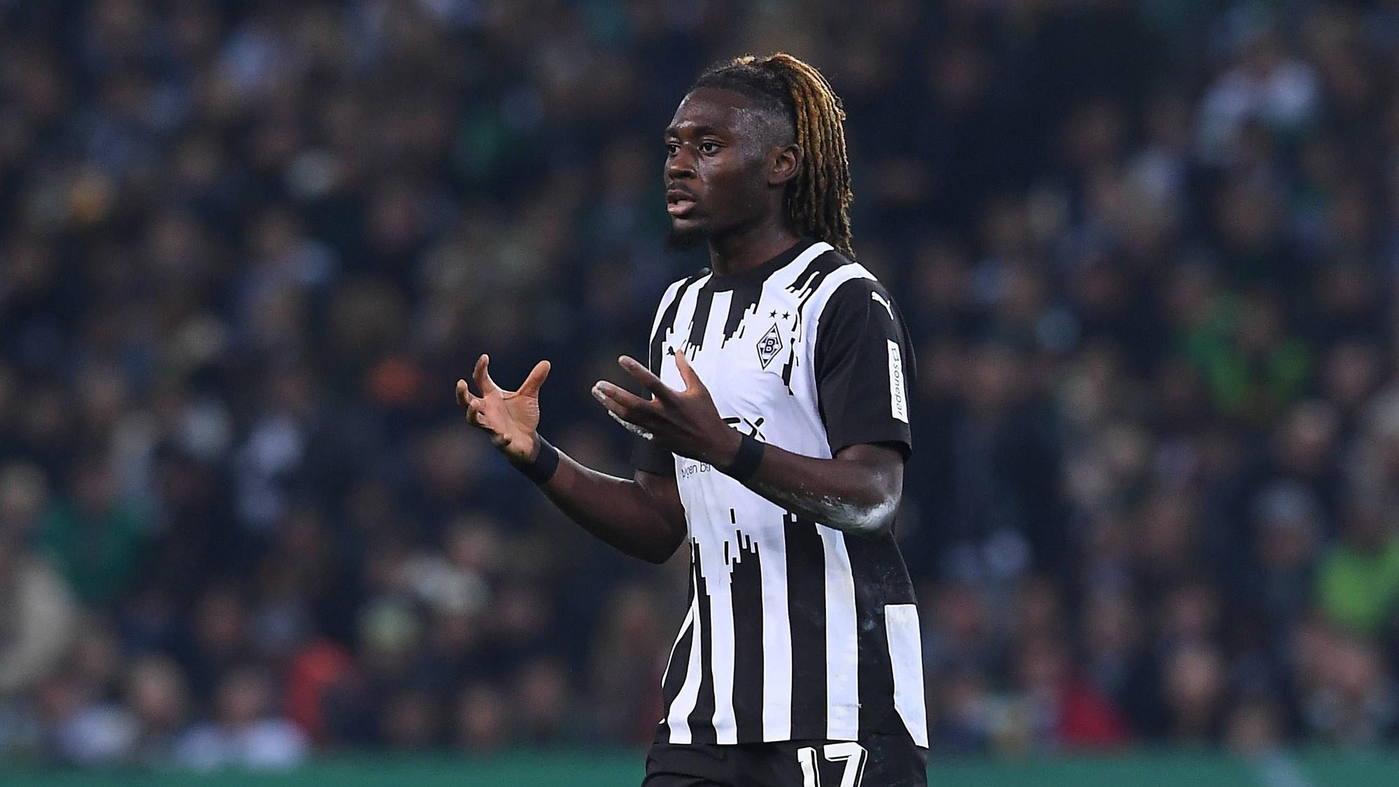 Manu Koné reißt bei einem Borussia-Spiel beide Arme vor seinen Körper.