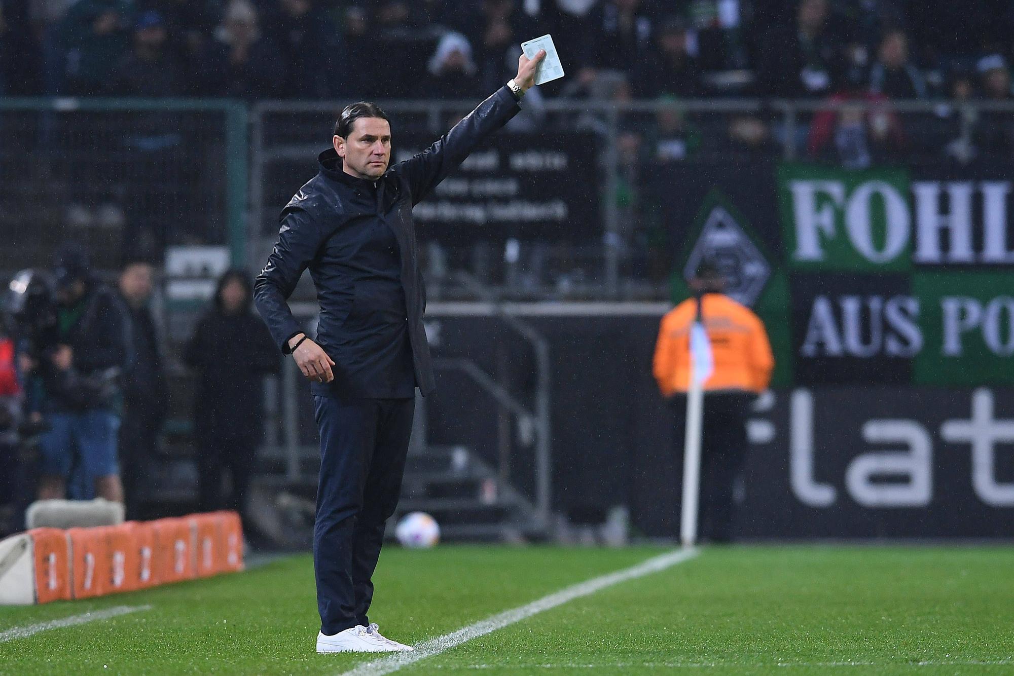 Coach von Borussia Mönchengladbach hält einen Zettel in der rechen Hand.