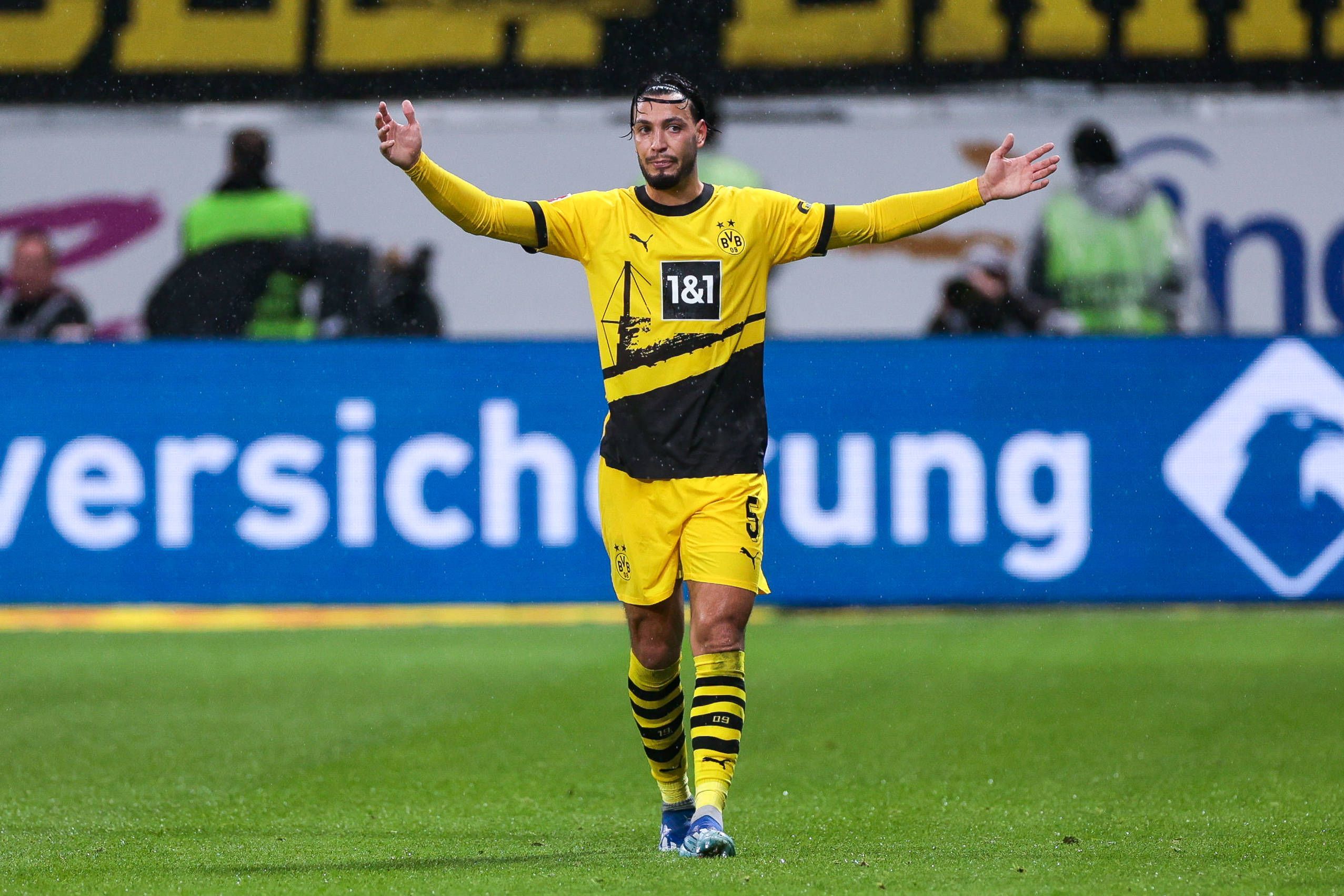 Ramy Bensebaini streckt beide Arme zur Seite.