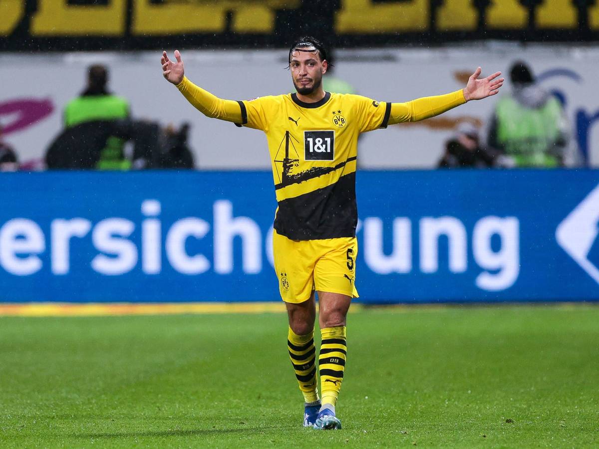 Ramy Bensebaini streckt beide Arme zur Seite.