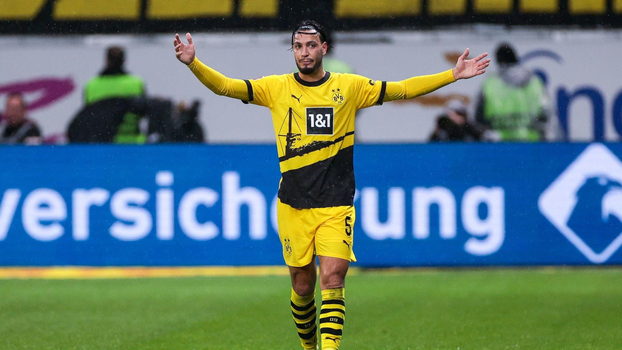 Ramy Bensebaini streckt beide Arme zur Seite.