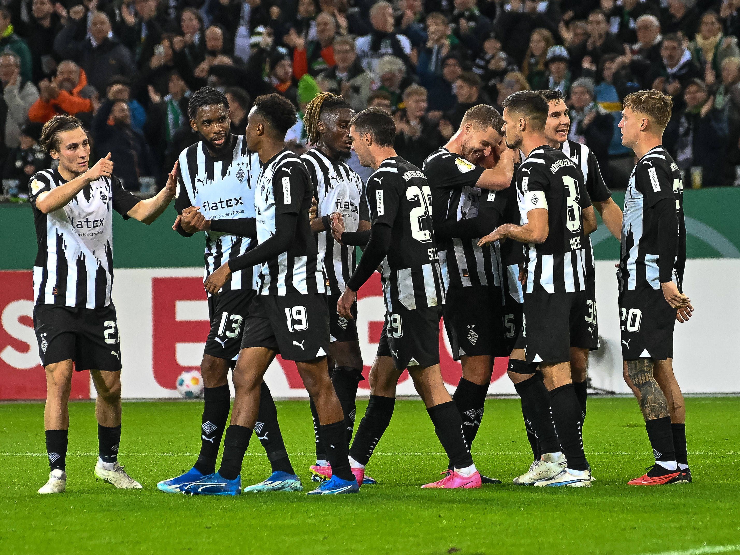 Mehrere Gladbachspieler jubeln gemeinsam im schwarz-weißen Trikot.