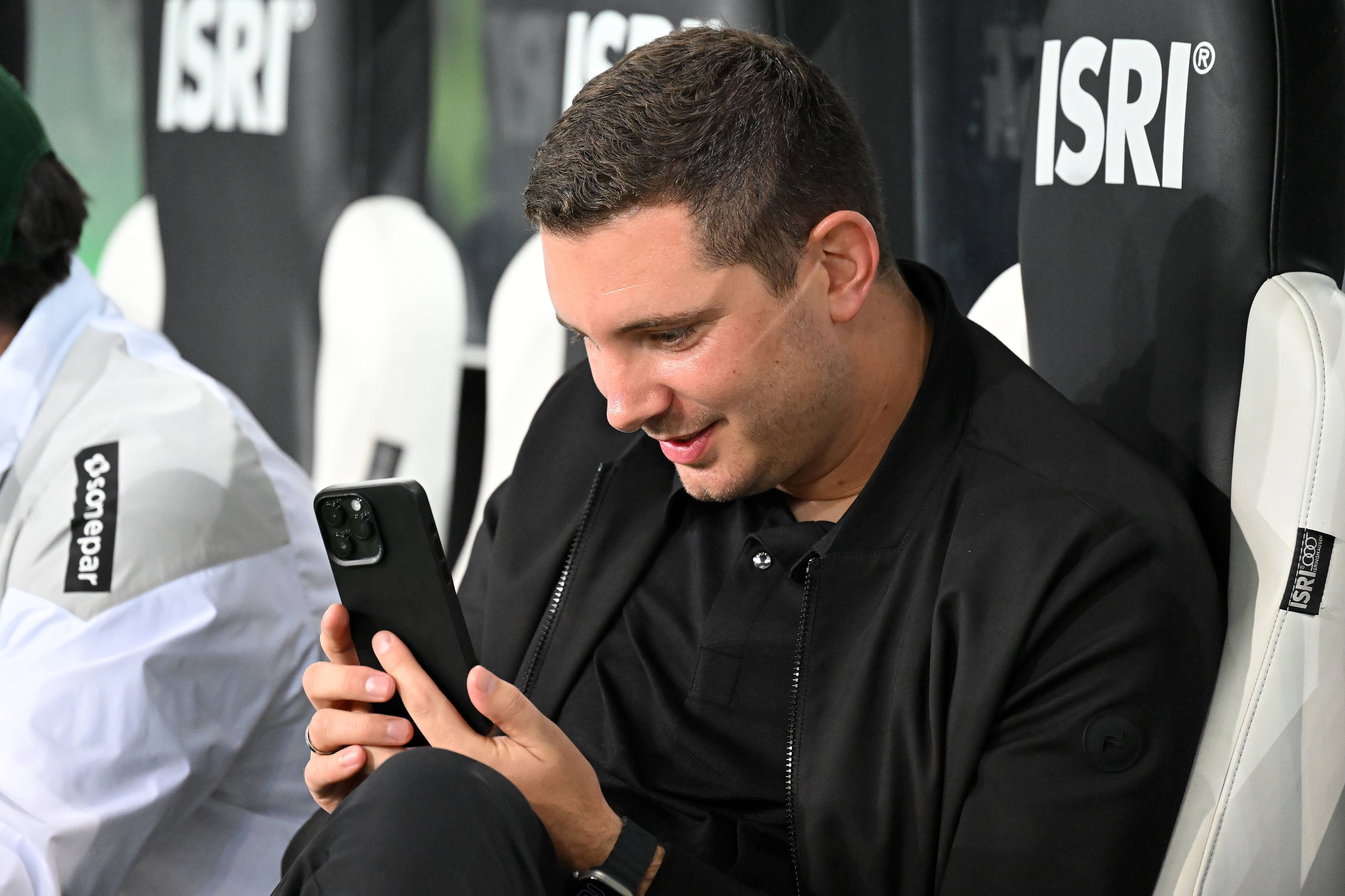 Nils Schmadtke schaut begeistert auf sein Smartphone.